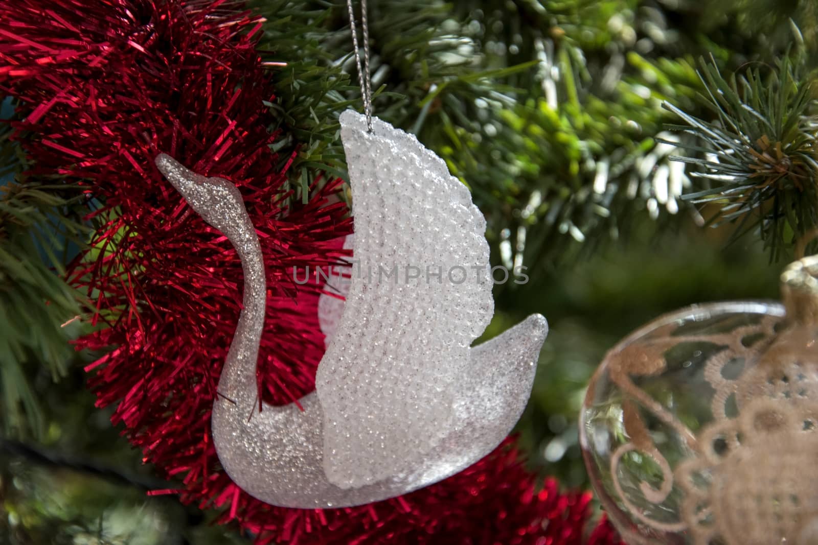 glass swan ornament hanging on christmas tree. Beautiful close up holiday photo. 
