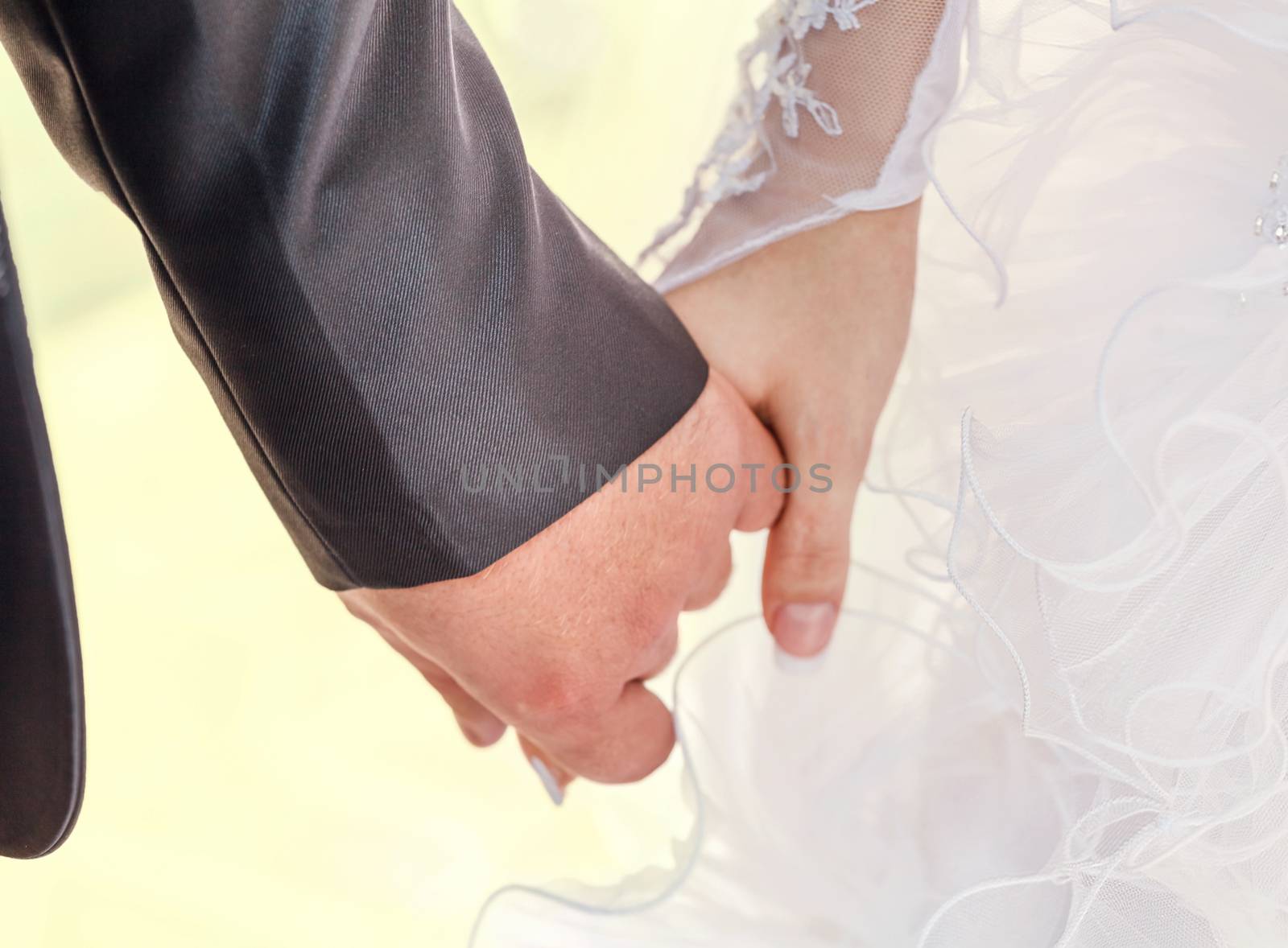 Wedding couple holding hands by fogen