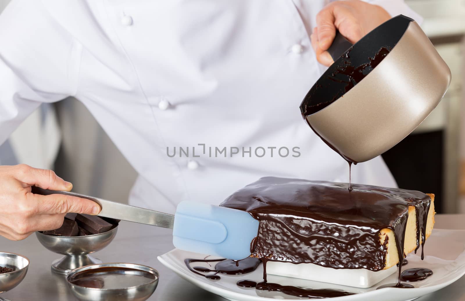 Pastry chef in the kitchen decorating a cake of chocolate