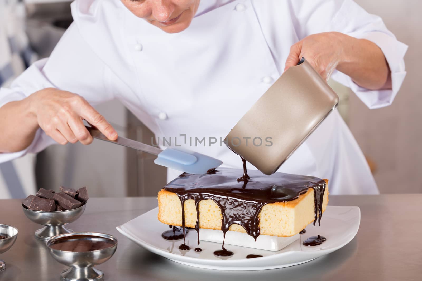 Pastry chef in the kitchen decorating a cake of chocolate