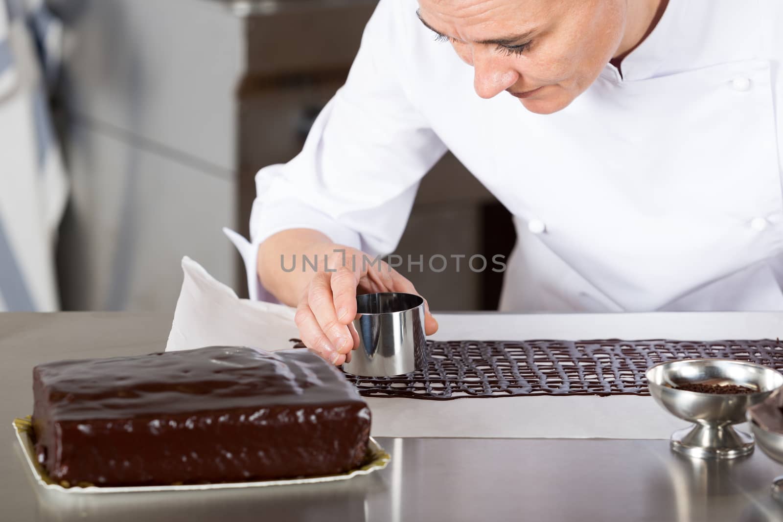 Pastry chef in the kitchen decorating a cake of chocolate