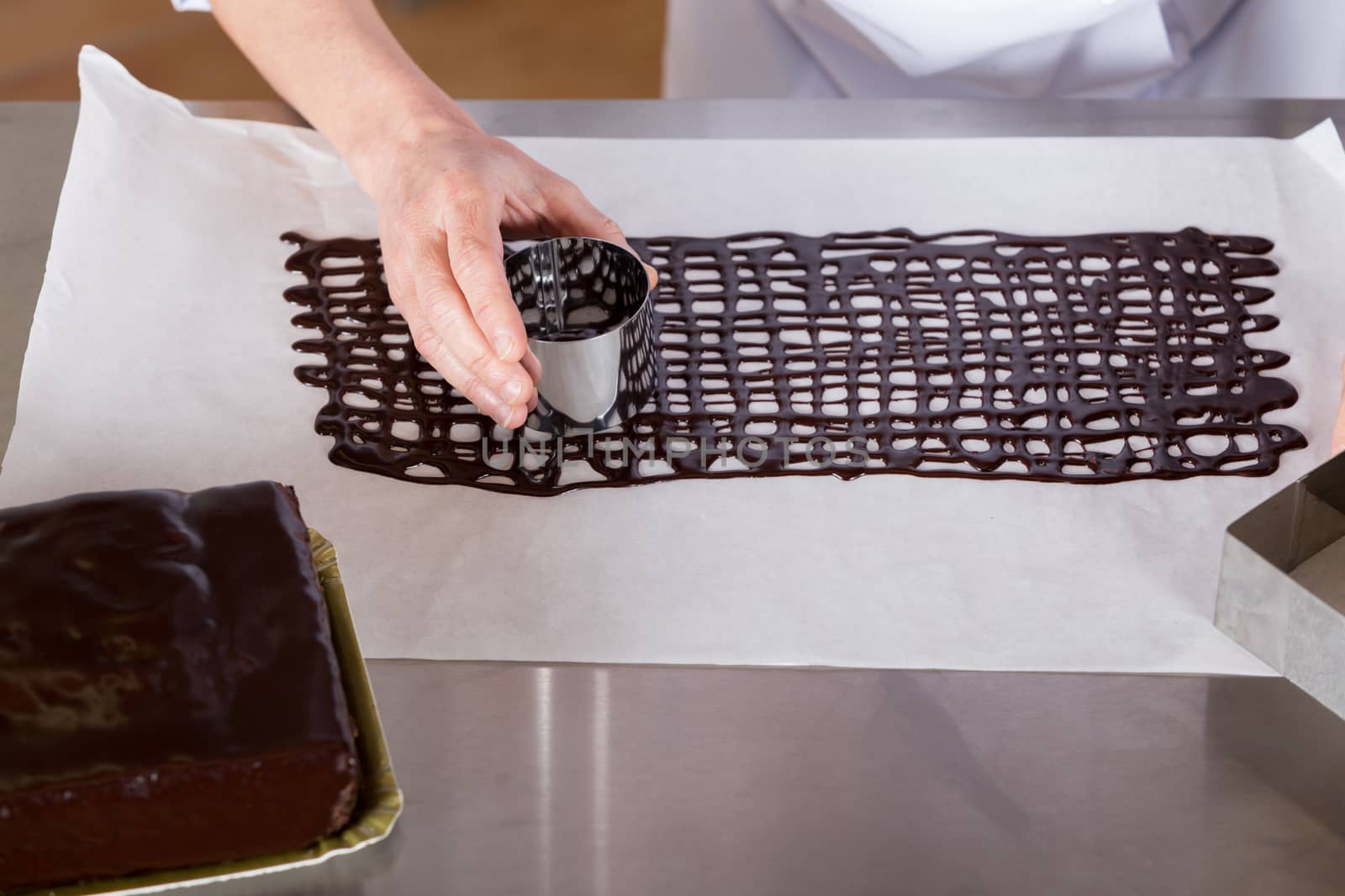 Pastry chef in the kitchen decorating a cake of chocolate