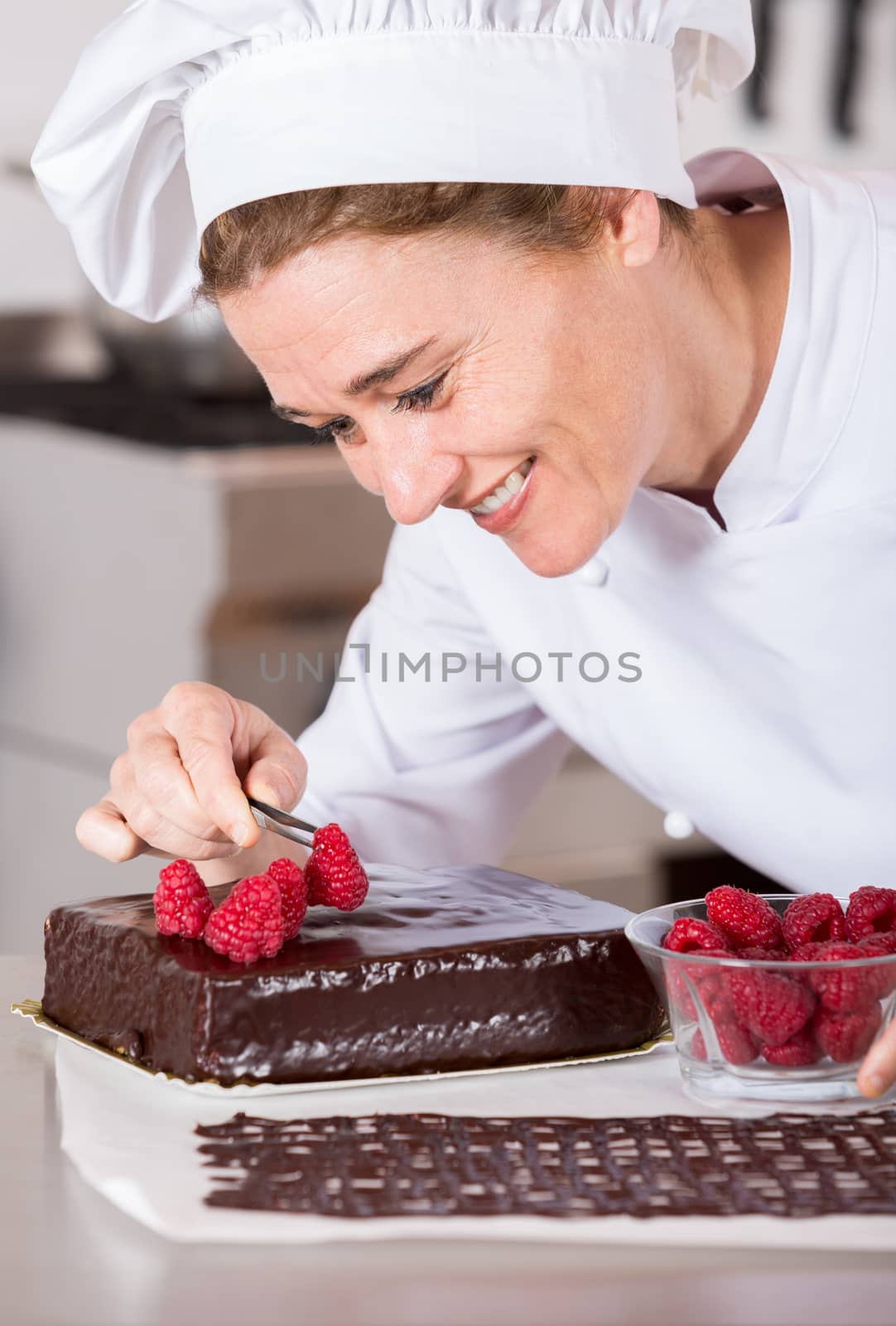 Pastry chef in the kitchen decorating a cake of chocolate