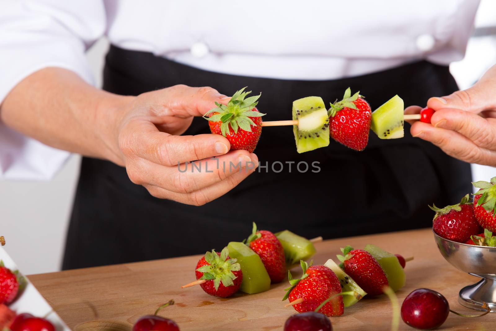 Chef preparing a variety of mixed fruit skewers
