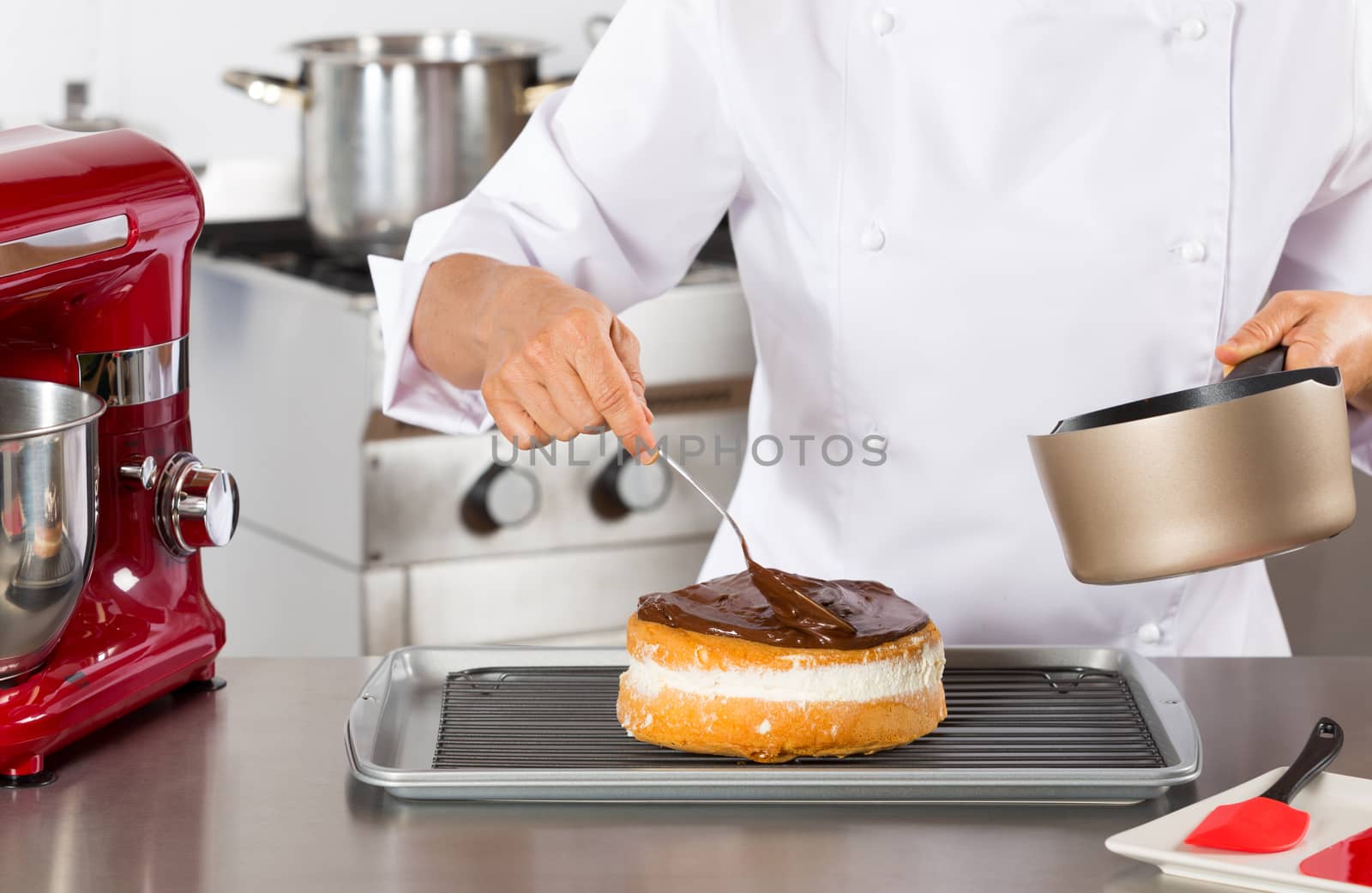 Pastry chef in the kitchen decorating a cake of chocolate