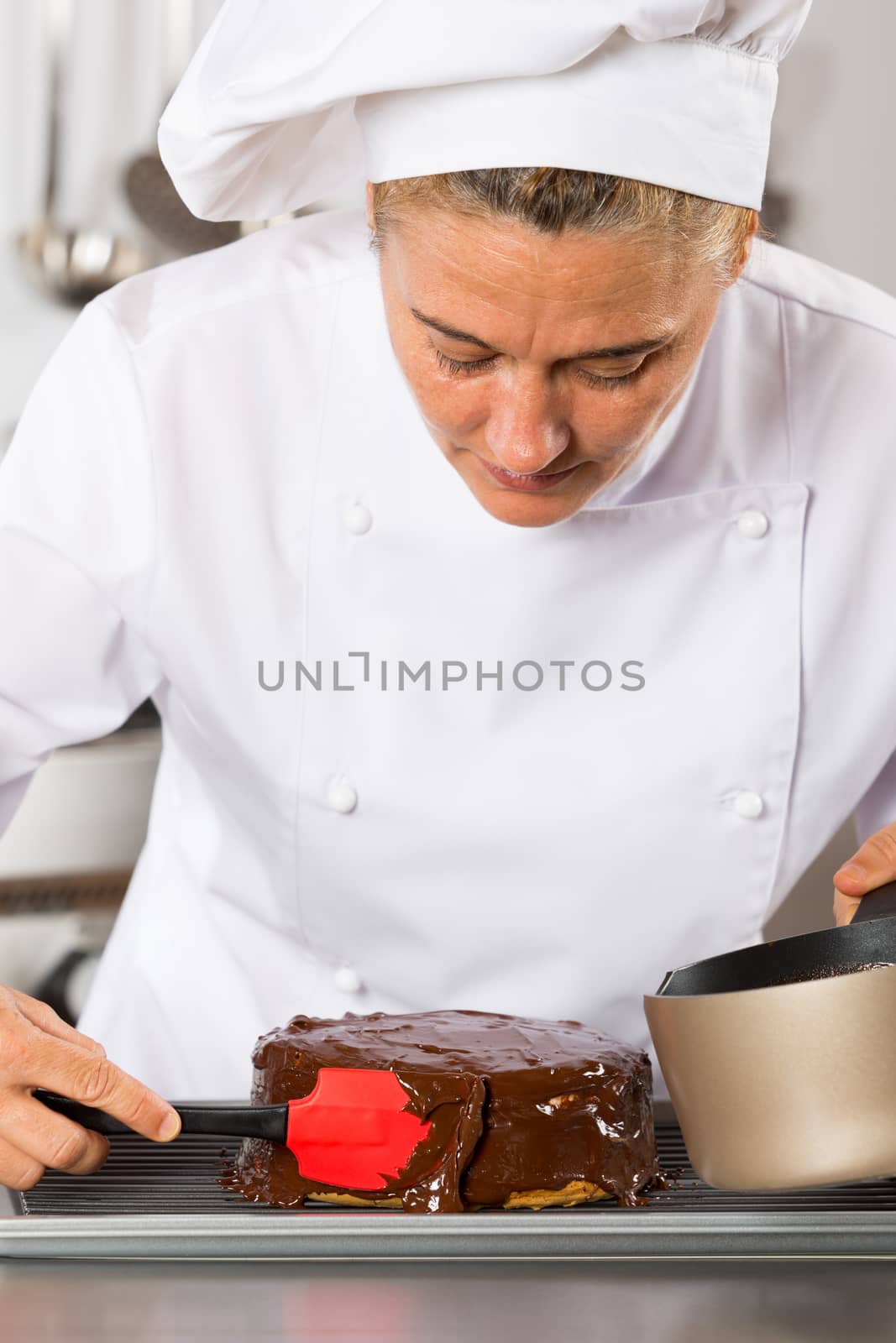 Pastry chef in the kitchen decorating a cake of chocolate