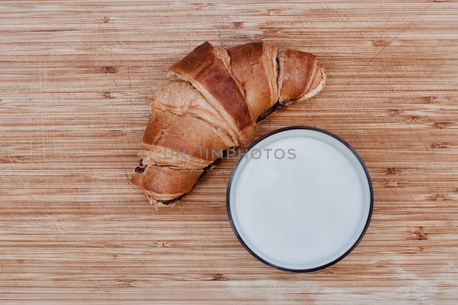 Fresh tasty milk and chocolate croissant on the wooden board.
