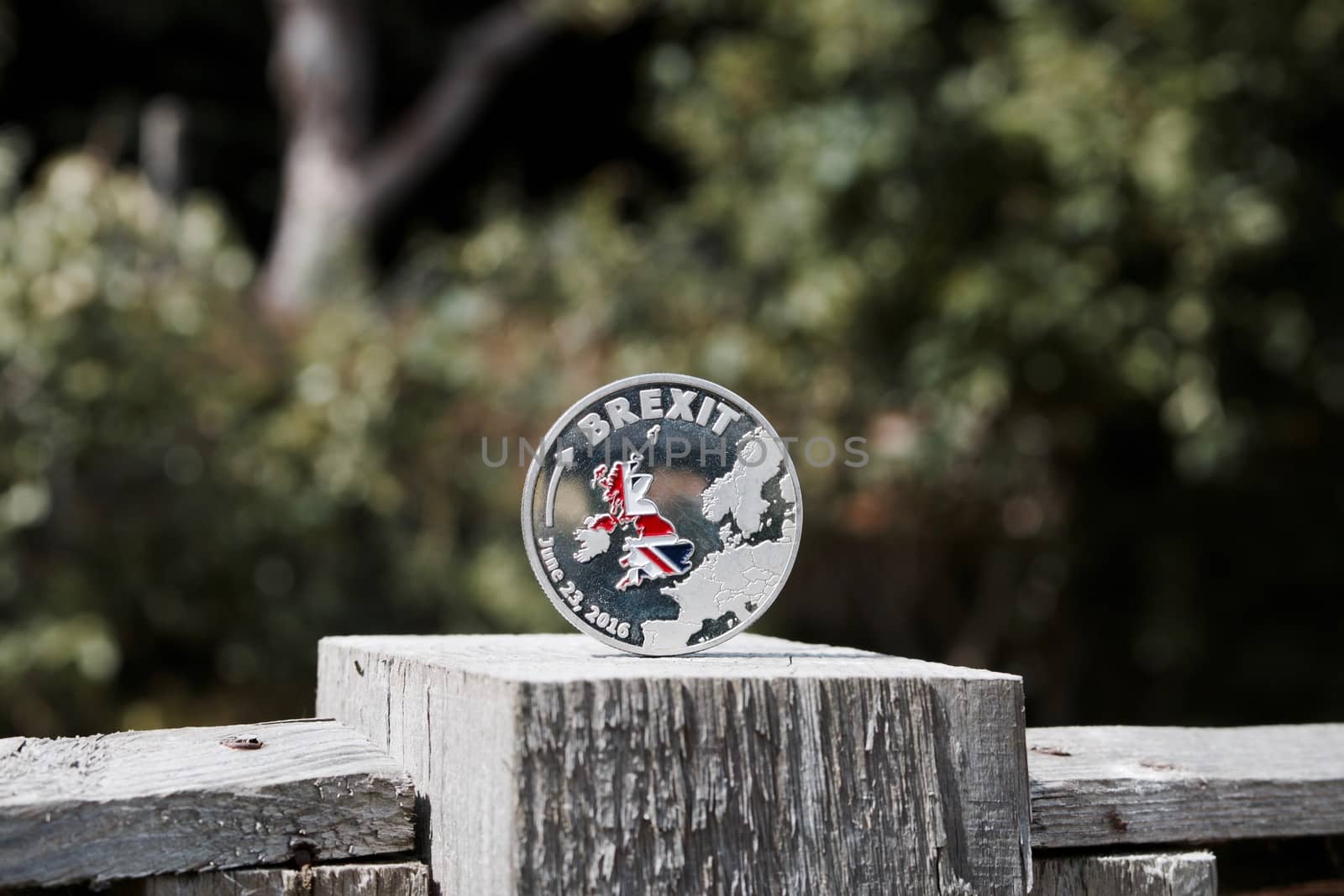 Europe leaving. Silver brexit coin with british map on the wooden fence in garden.