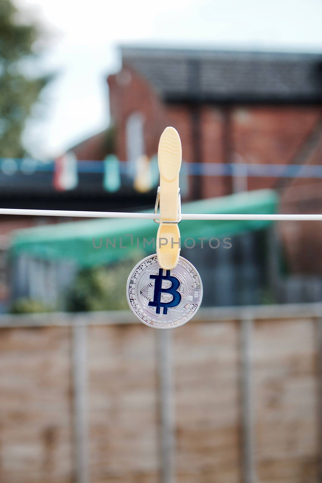 Digital currency physical silver bitcoin coin in garden with laundry clips.