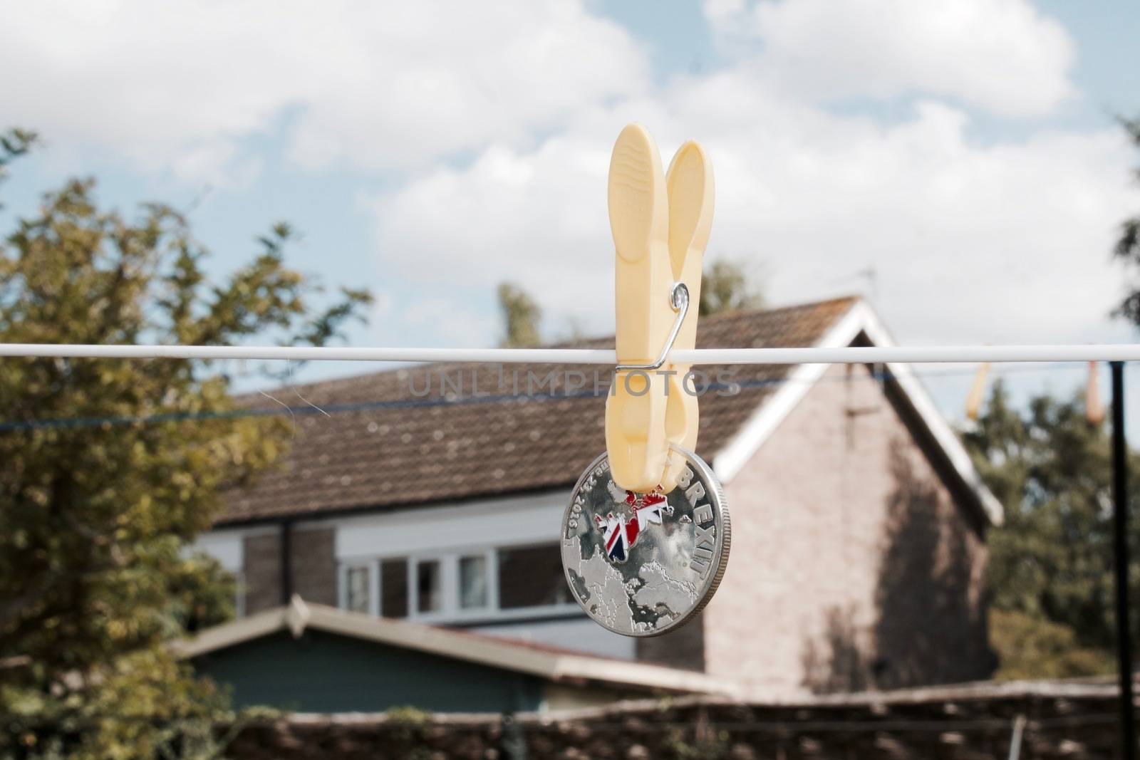 Europe leaving. Silver brexit coin with british map and yellow laundry clips on the line.