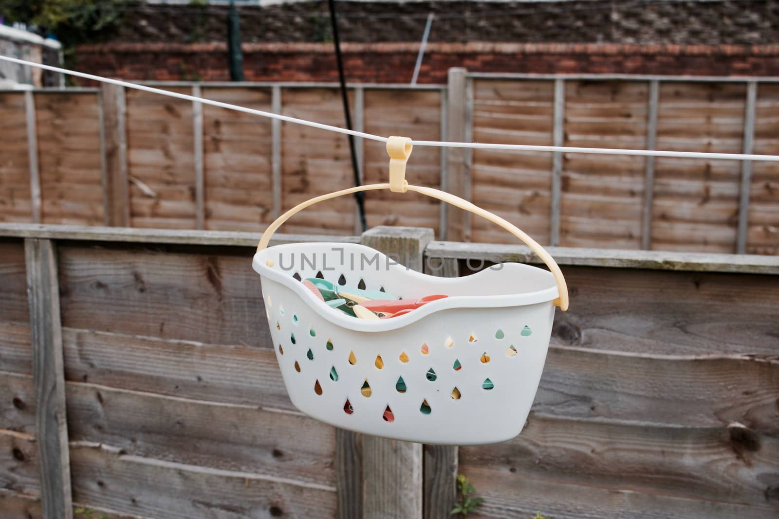 White basket with a colorful laundry clips in the garden on white line.