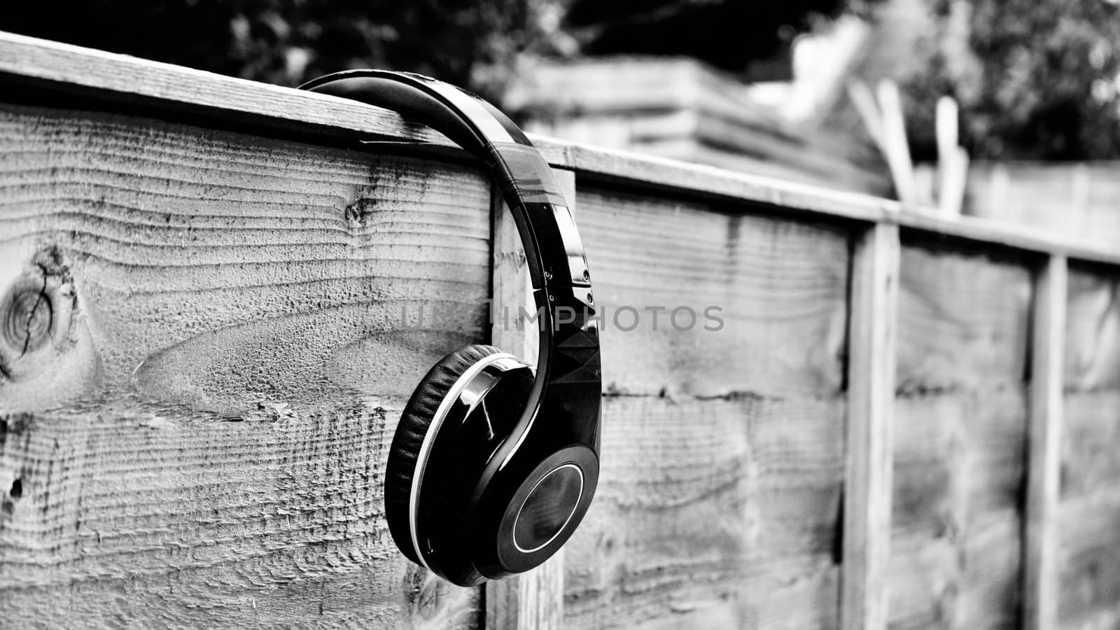 Black dirty headphones on the wall in garden. Black and white concept.