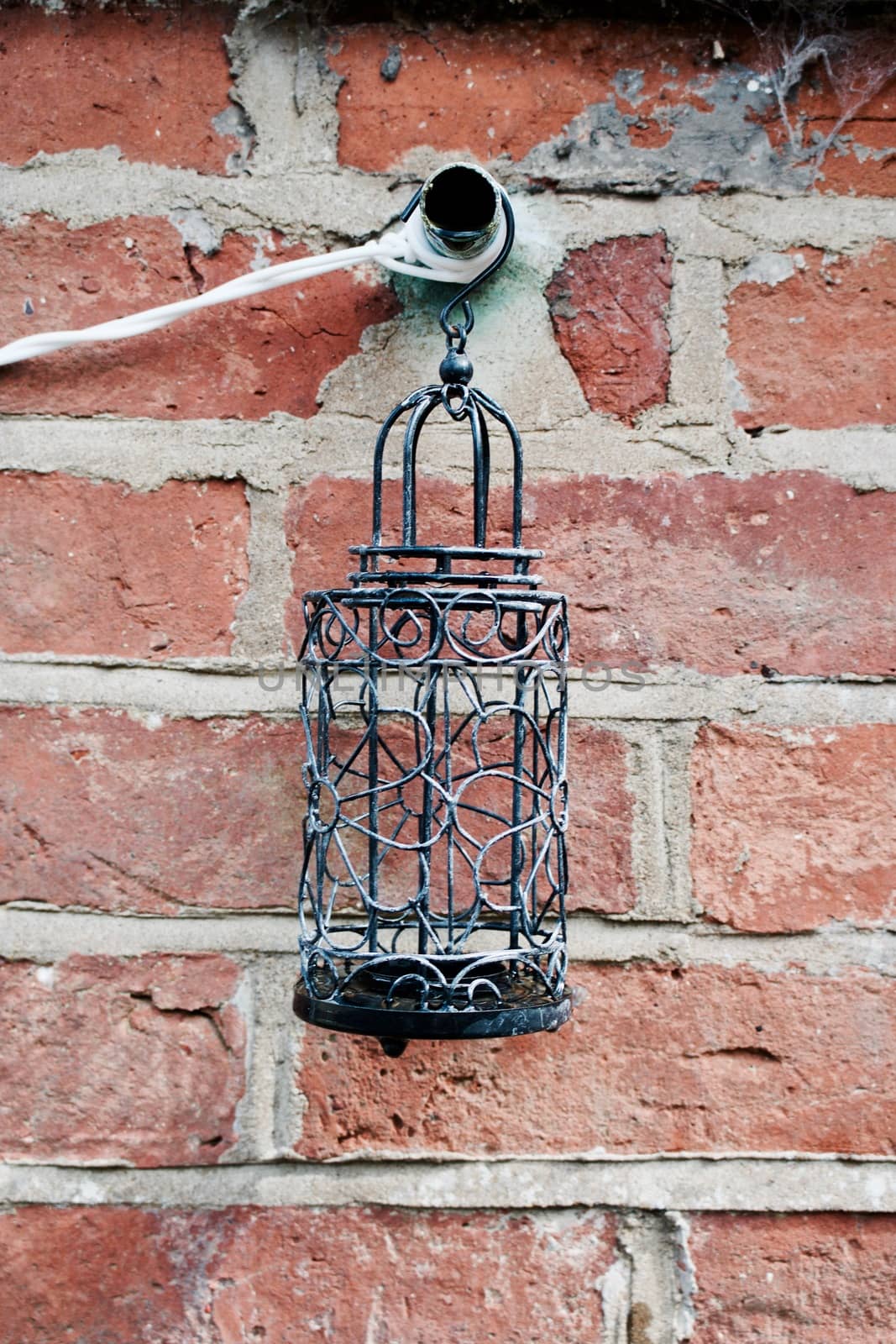 Old brick wall and black candle holder with water in the garden.