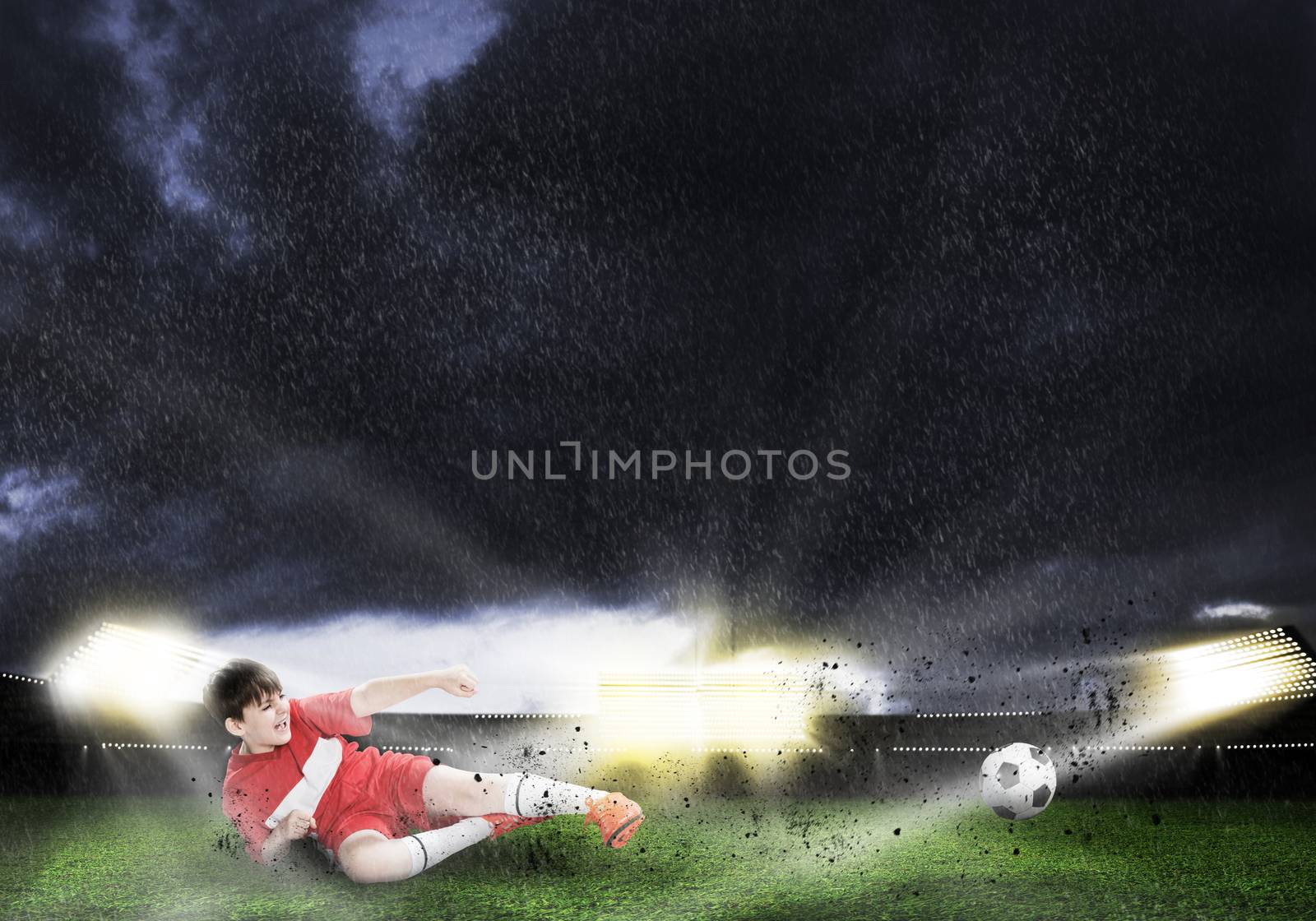 Excited boy football player at stadium kicking ball