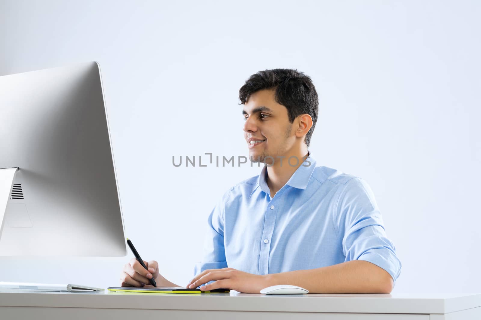 Young graphic designer sitting at desk and working