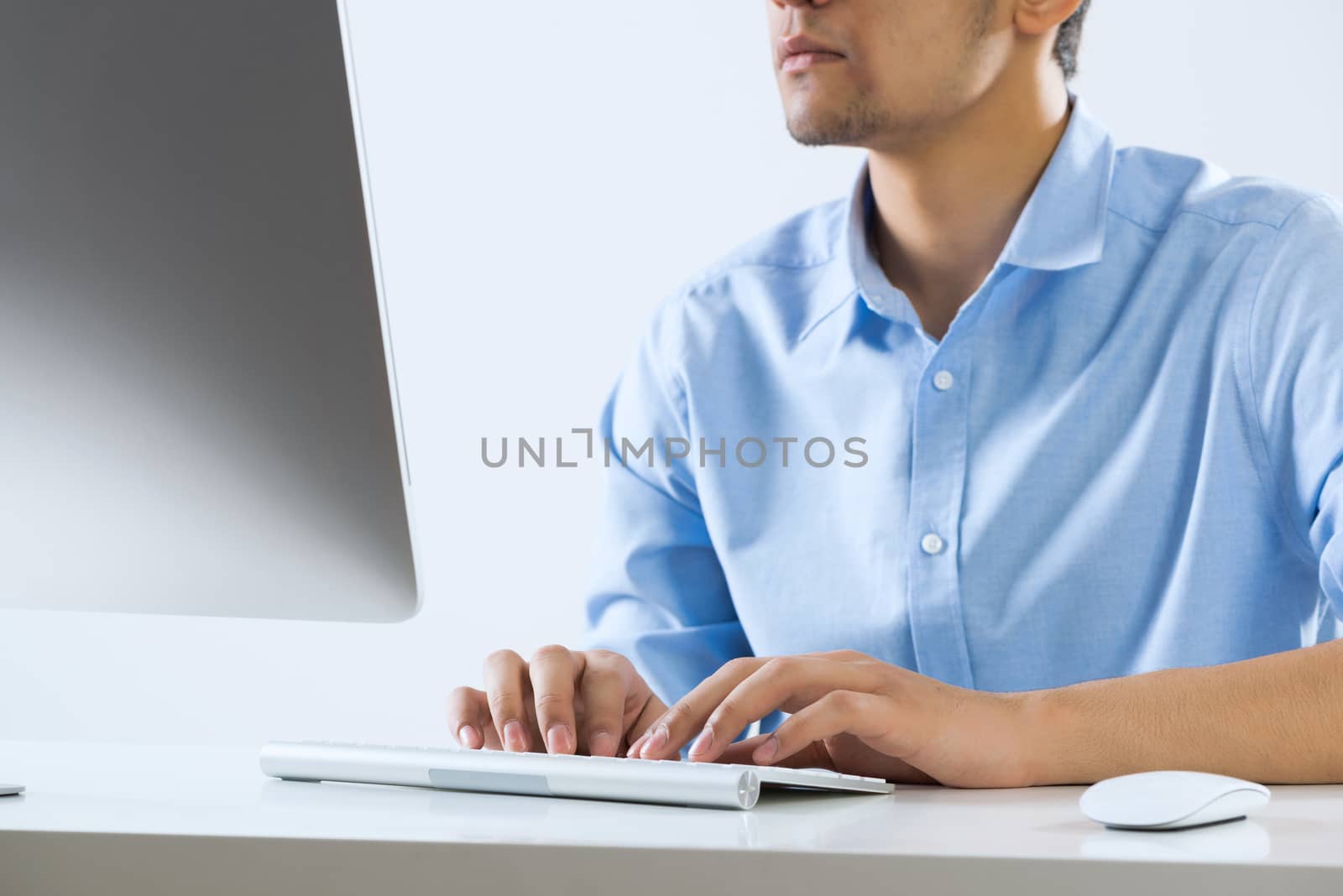 Young man sitting at desk and typing on keyboard