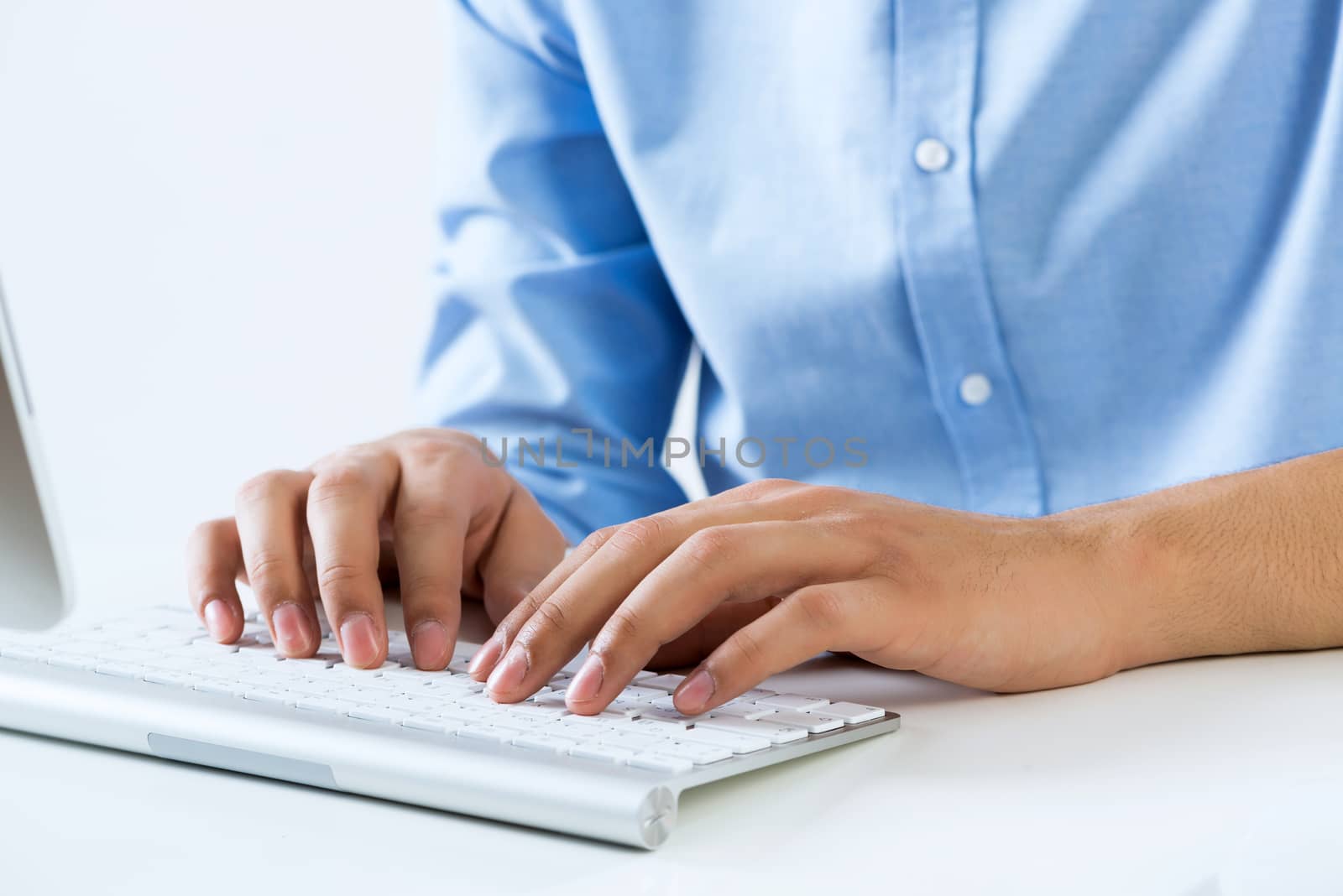 Young man sitting at desk and typing on keyboard