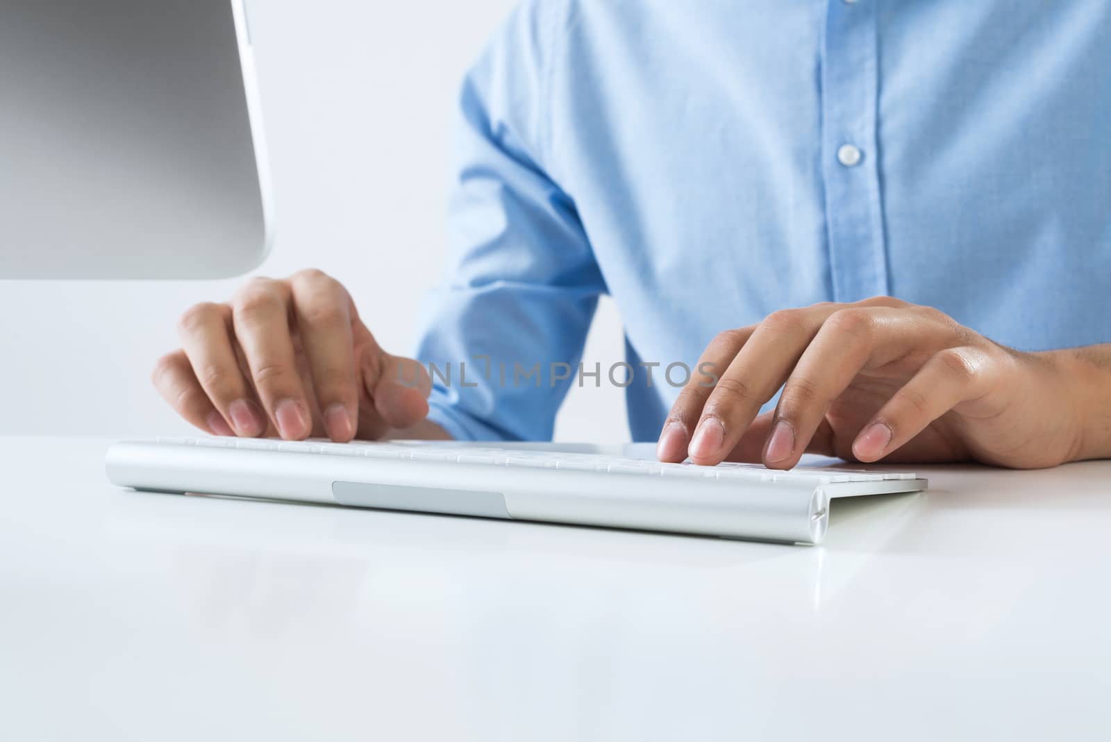 Young man sitting at desk and typing on keyboard