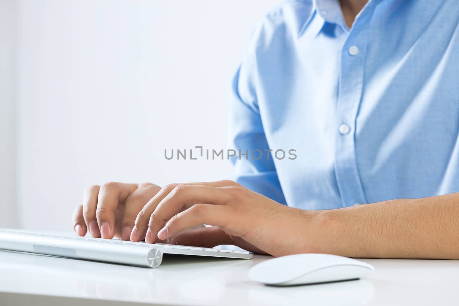 Young man sitting at desk and typing on keyboard