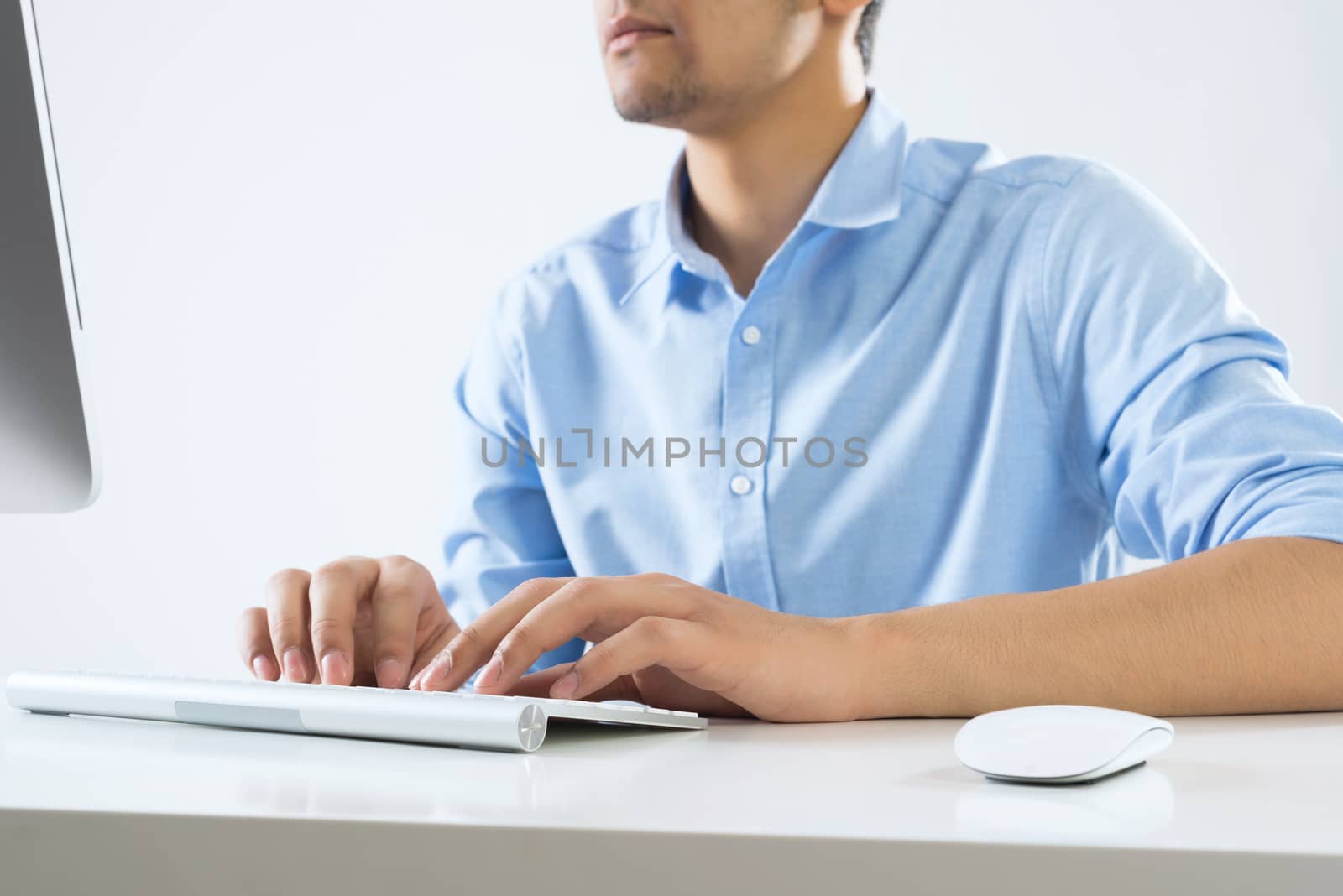 Young man sitting at desk and typing on keyboard