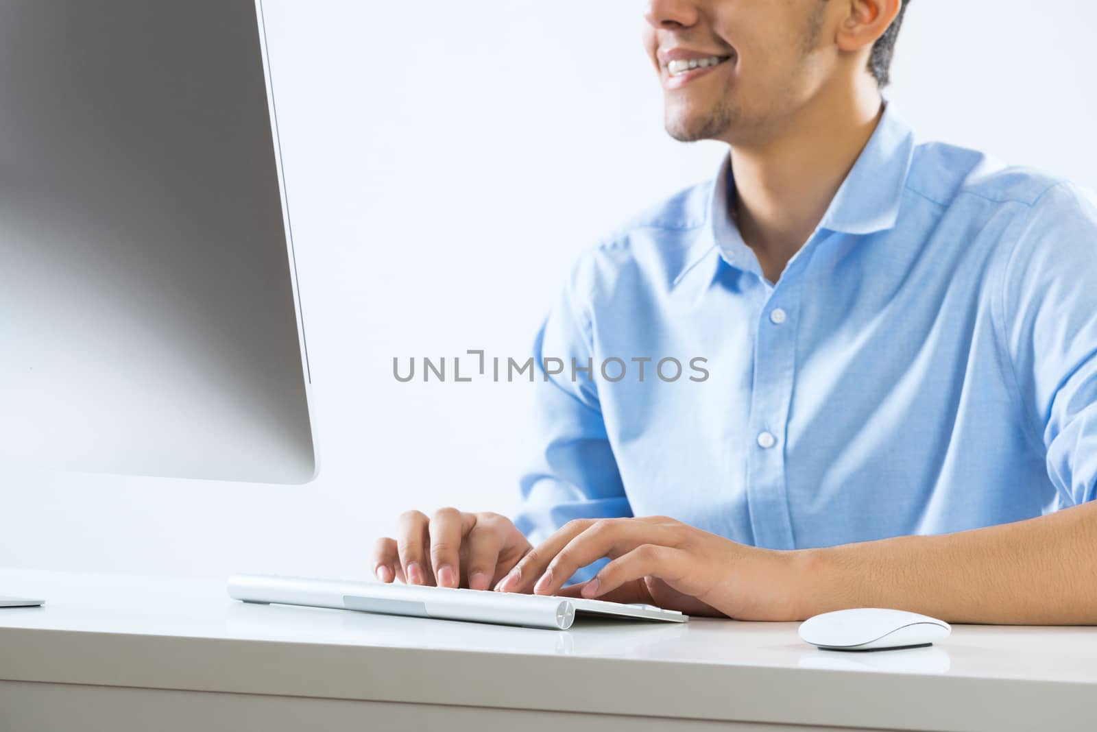 Young man sitting at desk and typing on keyboard