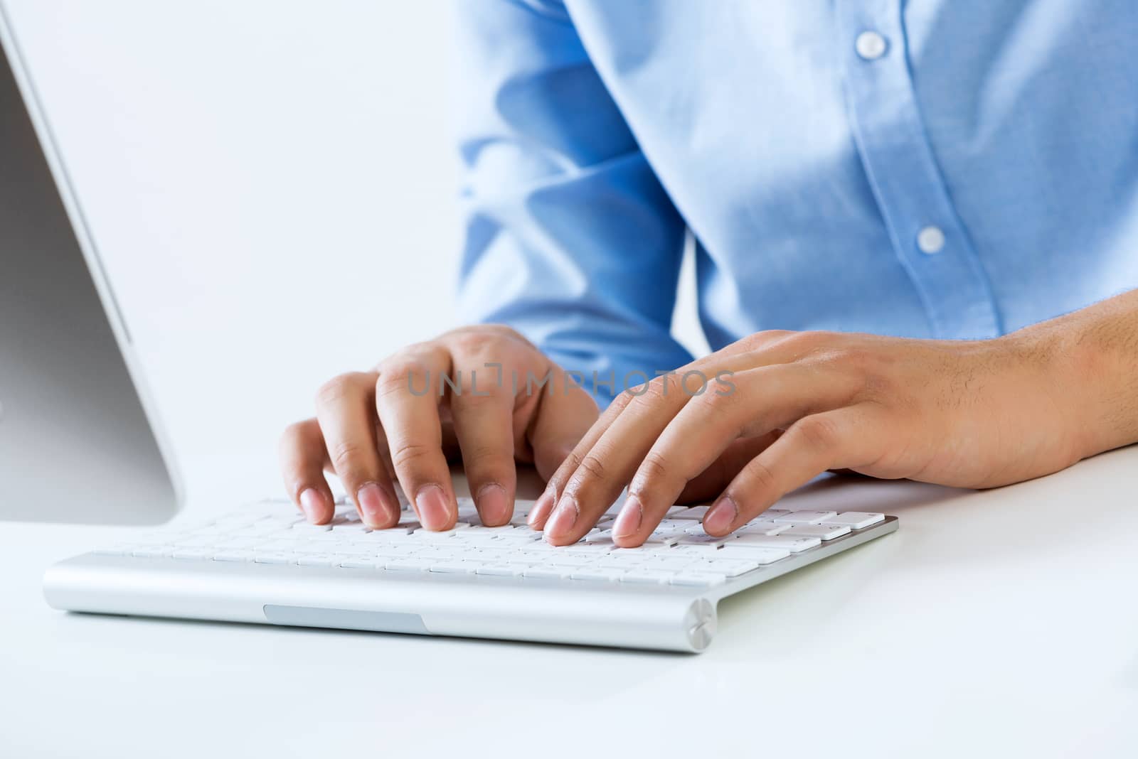 Young man sitting at desk and typing on keyboard