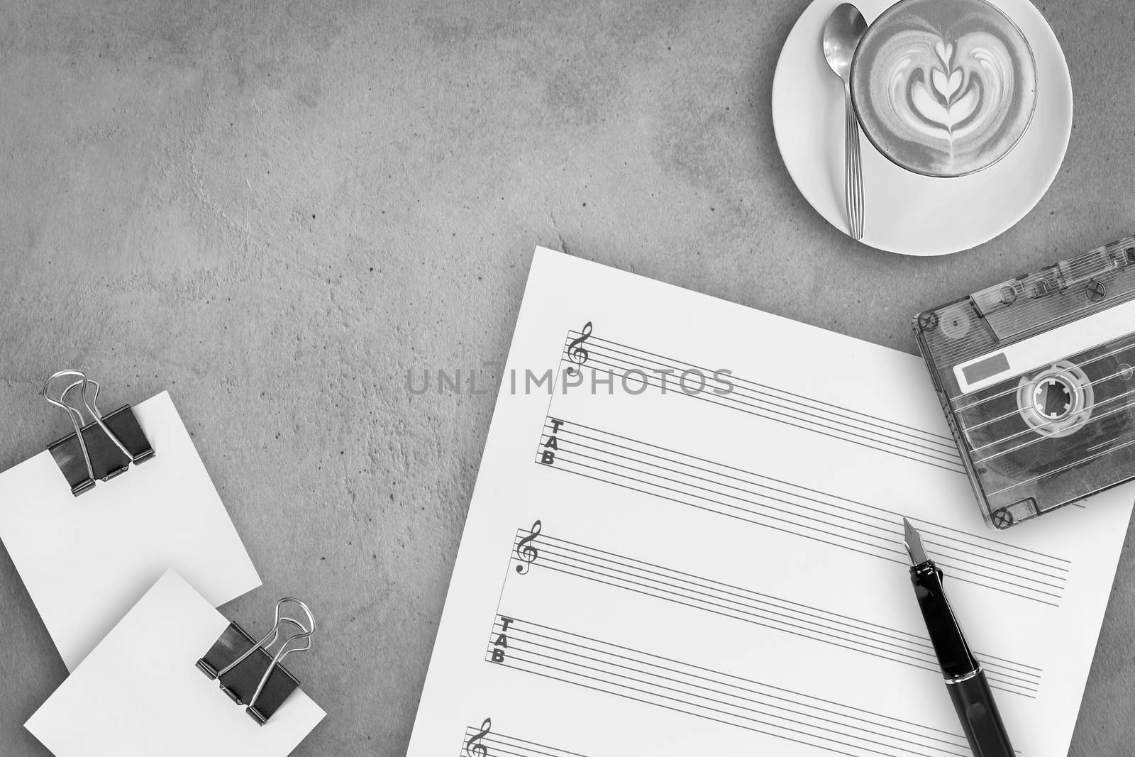 Sheet music, fountain pen, tape cassette and coffee latte on wooden table, top view picture