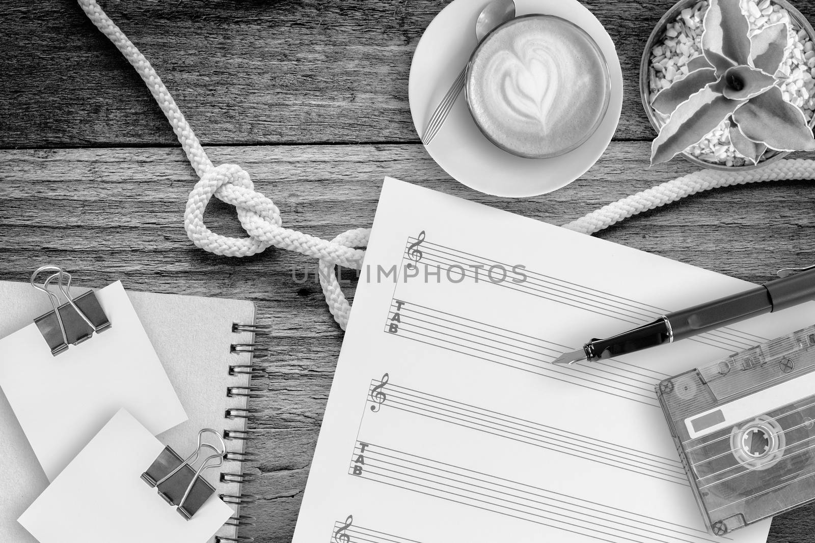 Sheet music, cactus, fountain pen, tape cassette and coffee latte on vintage wooden table