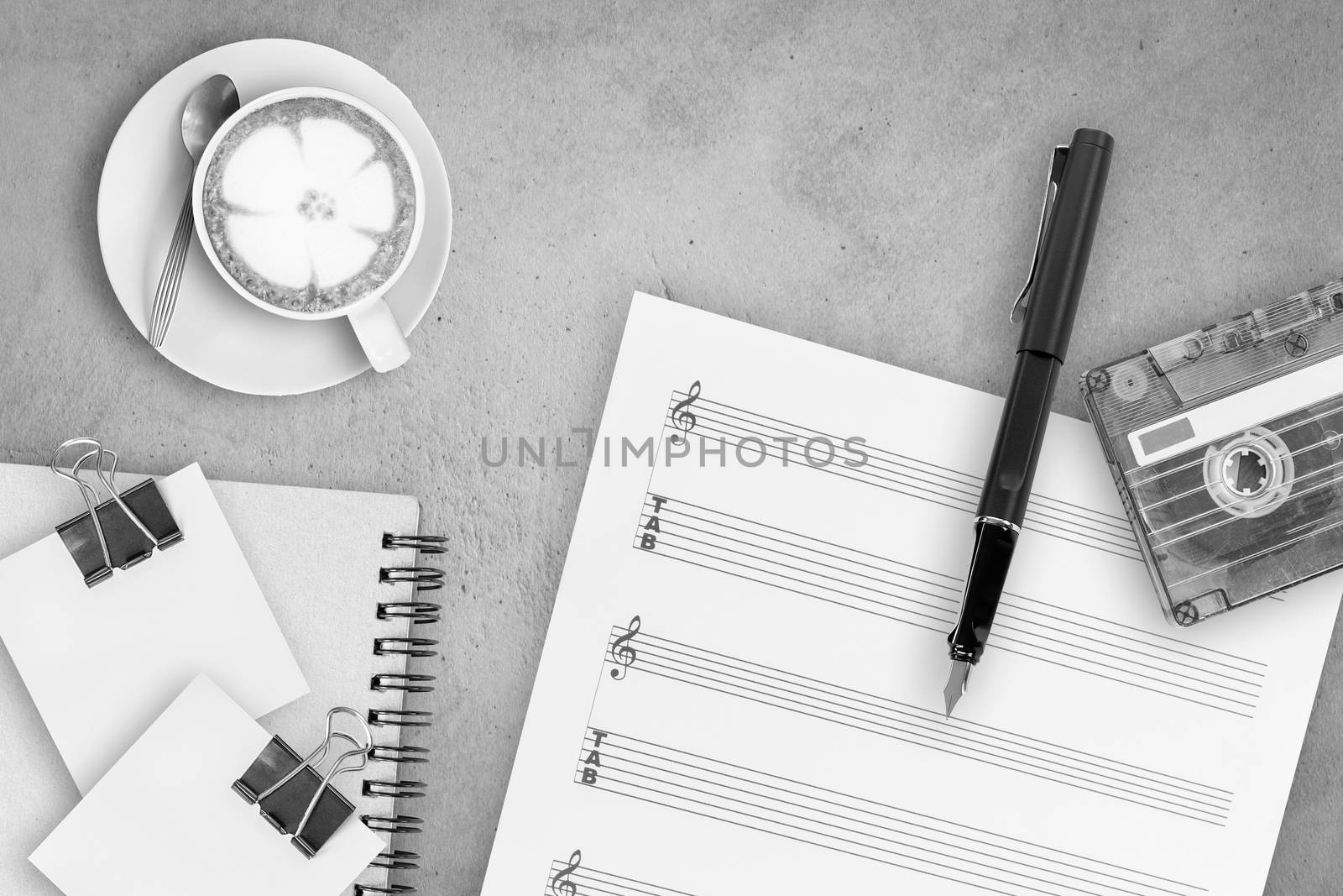 Sheet music, fountain pen, tape cassette and coffee latte on wooden table, top view picture