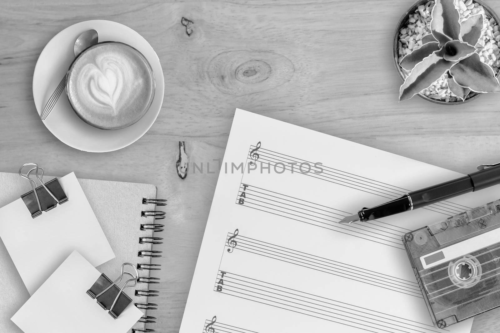 Sheet music, cactus, fountain pen, tape cassette and coffee latte on wooden table, top view picture