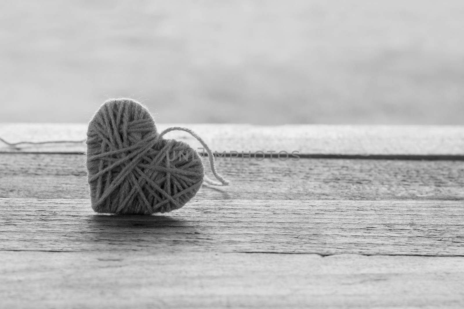 pink knitting wool in shape of heart on vintage wooden with bokeh soft light background