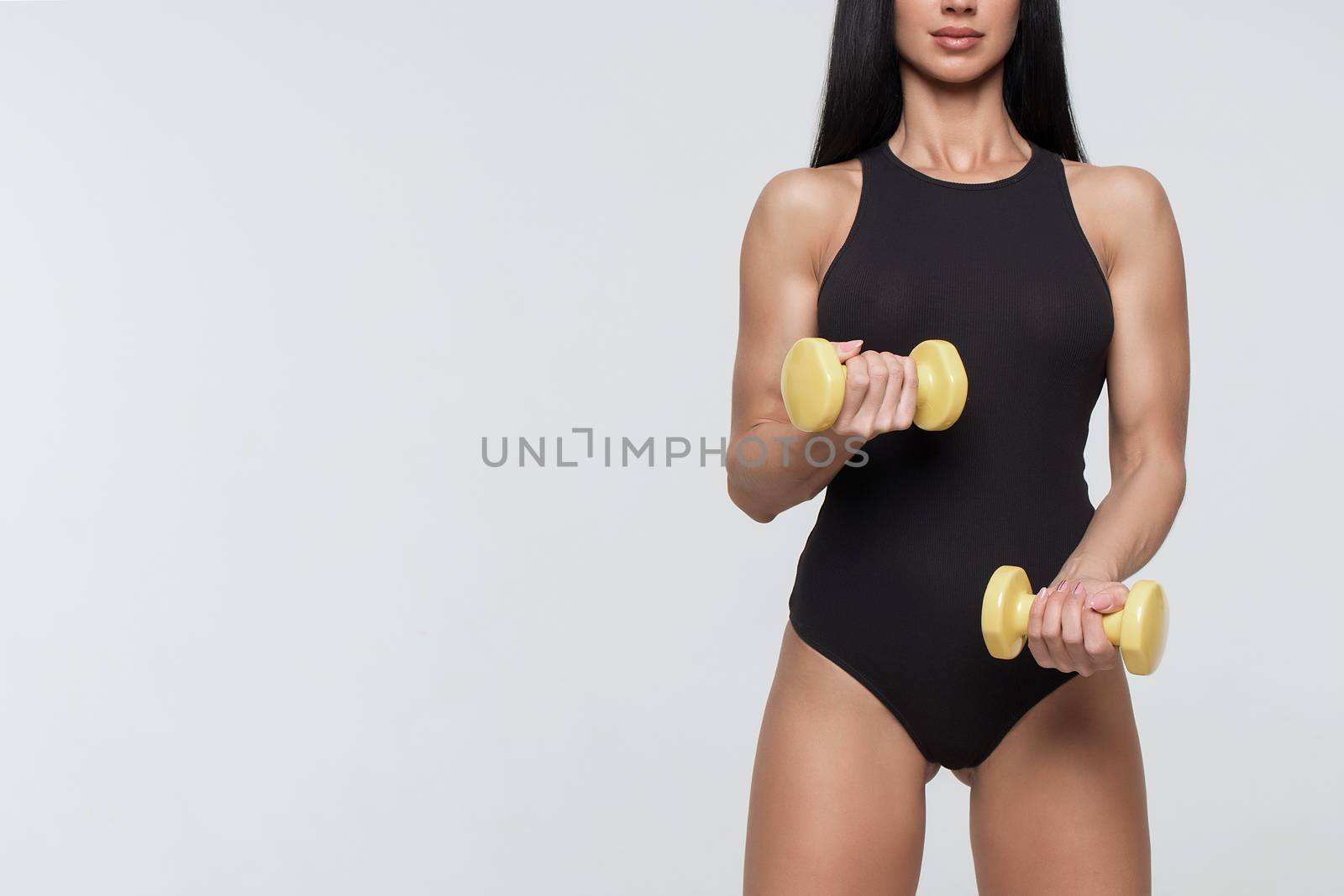 Fitness woman exercising crossfit holding dumbbell strength training biceps.