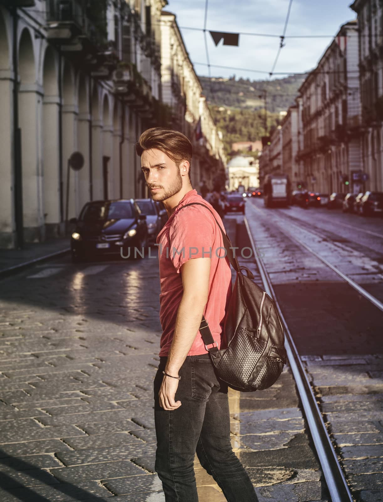 One handsome young man in urban setting in European city, Turin in Italy. Looking at camera, walking