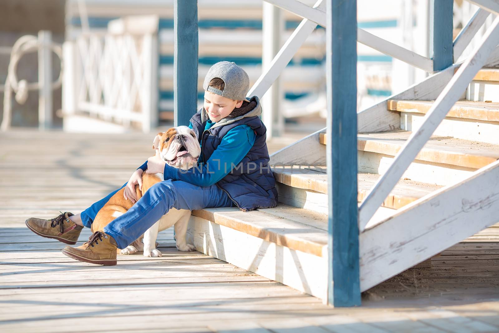 Nice looking handsome boy on beach with bulldog by dlukashenko@mail.ru