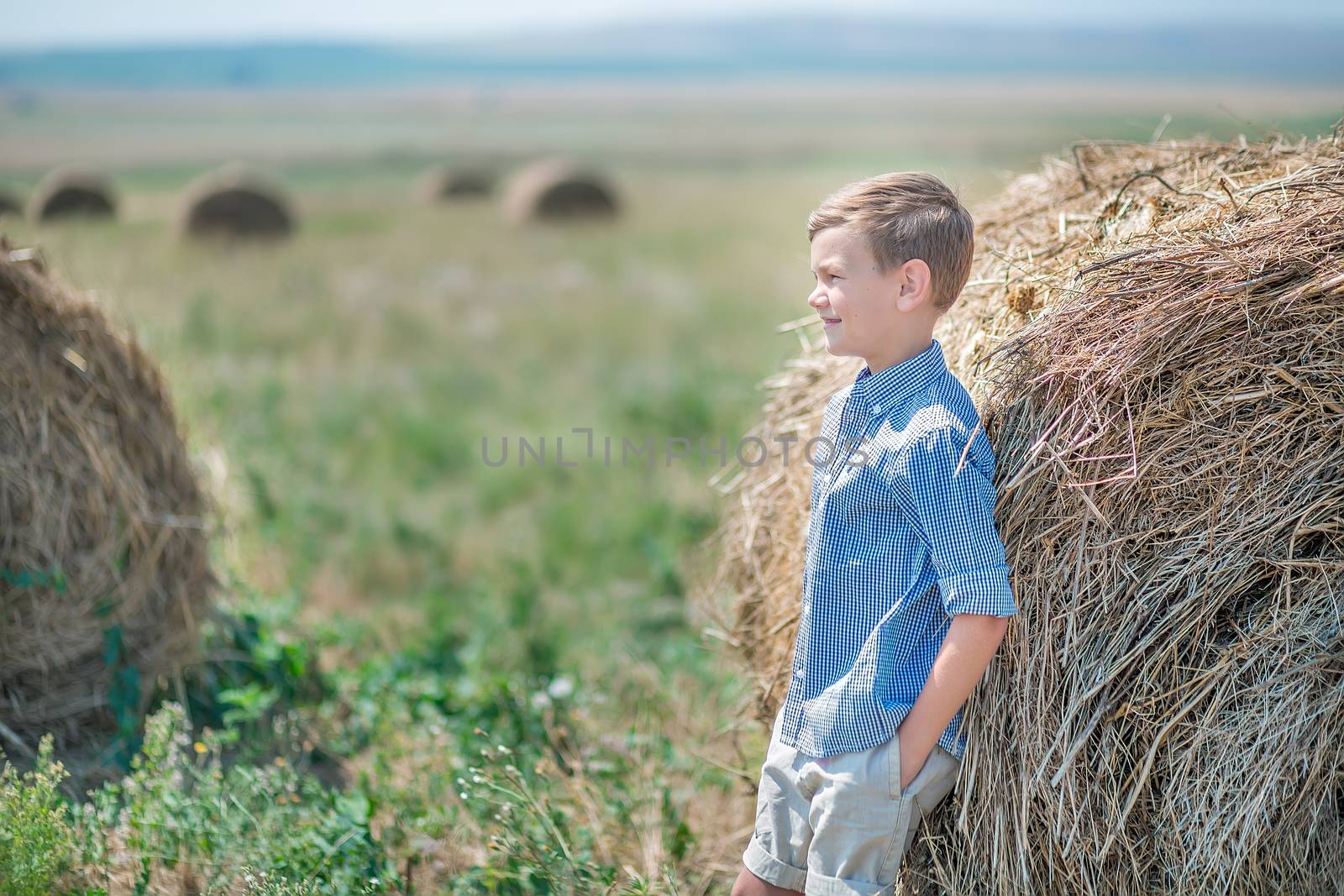 Attractive boy sitting on a haystack and smiling.