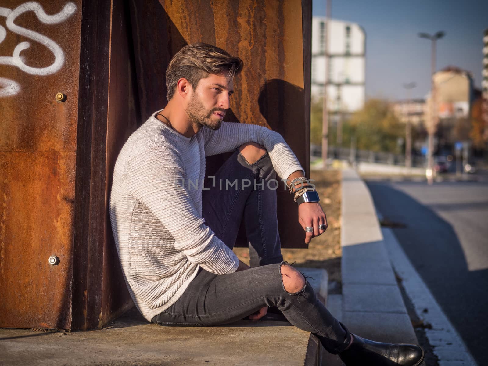 One handsome man in urban setting in European city, sitting