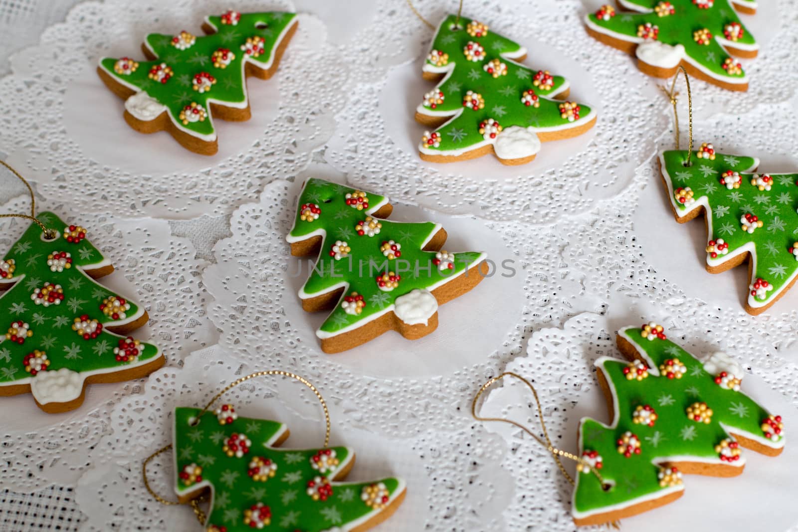 Painted gingerbread in the shape of Christmas tree on a white napkin background. Christmas trees cookies - colorful icing decoration