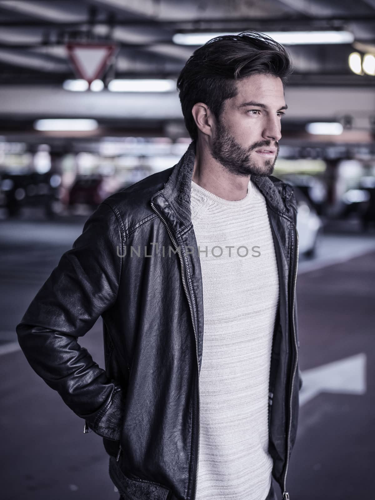 Handsome muscular man in casual clothing on background of parking.