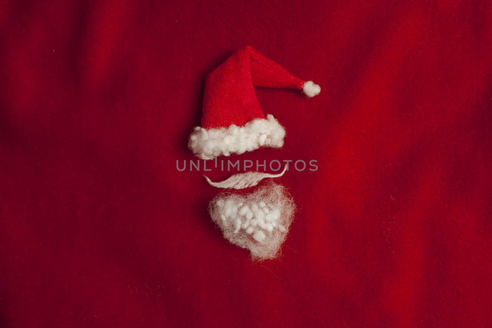 Red Santa Claus hat on red background minimalism, conceptual image. Holiday, Christmas New Year flat lay