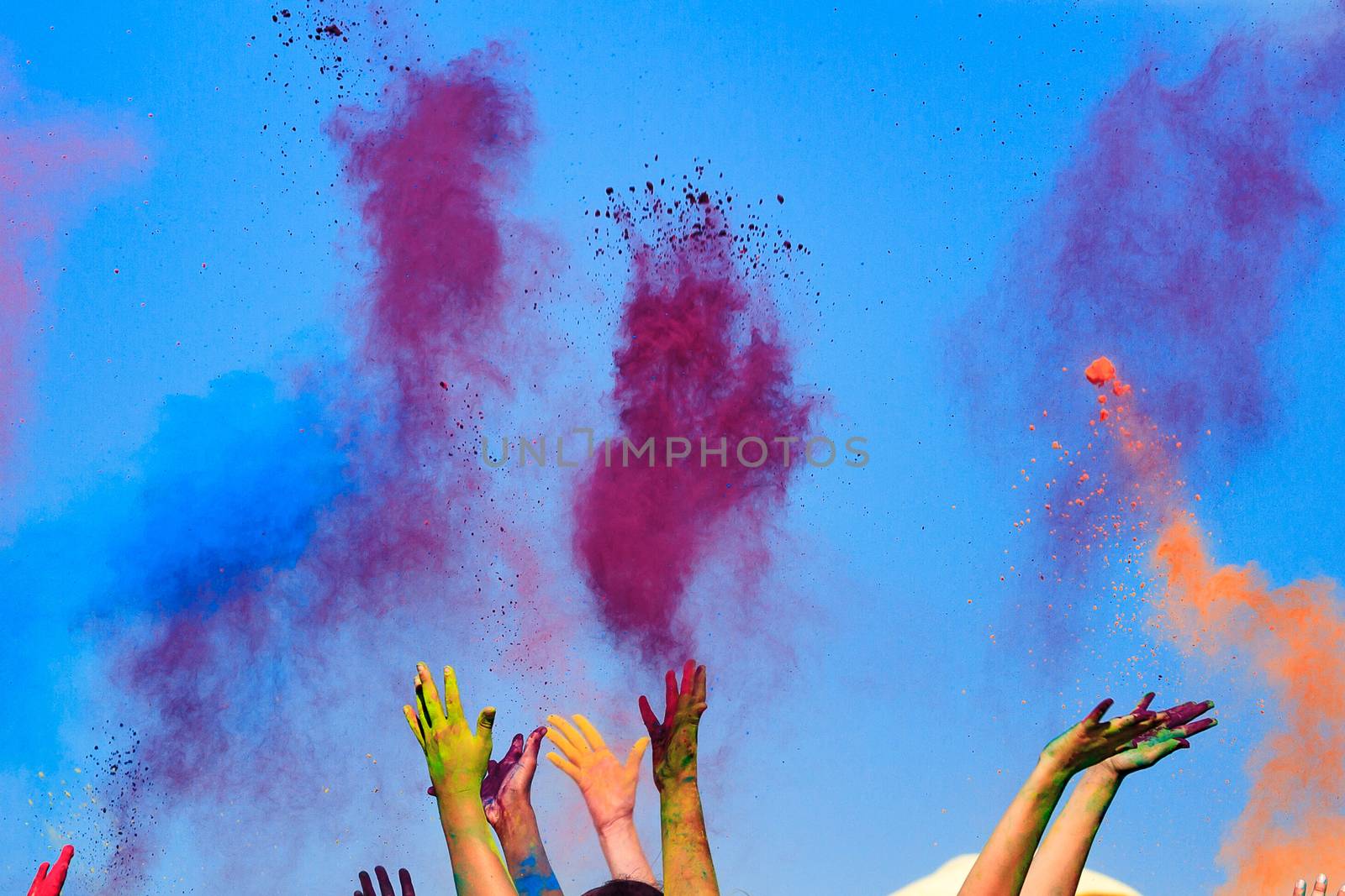 At the color Holi Festival, hands in the air, blue sky behind by Nobilior