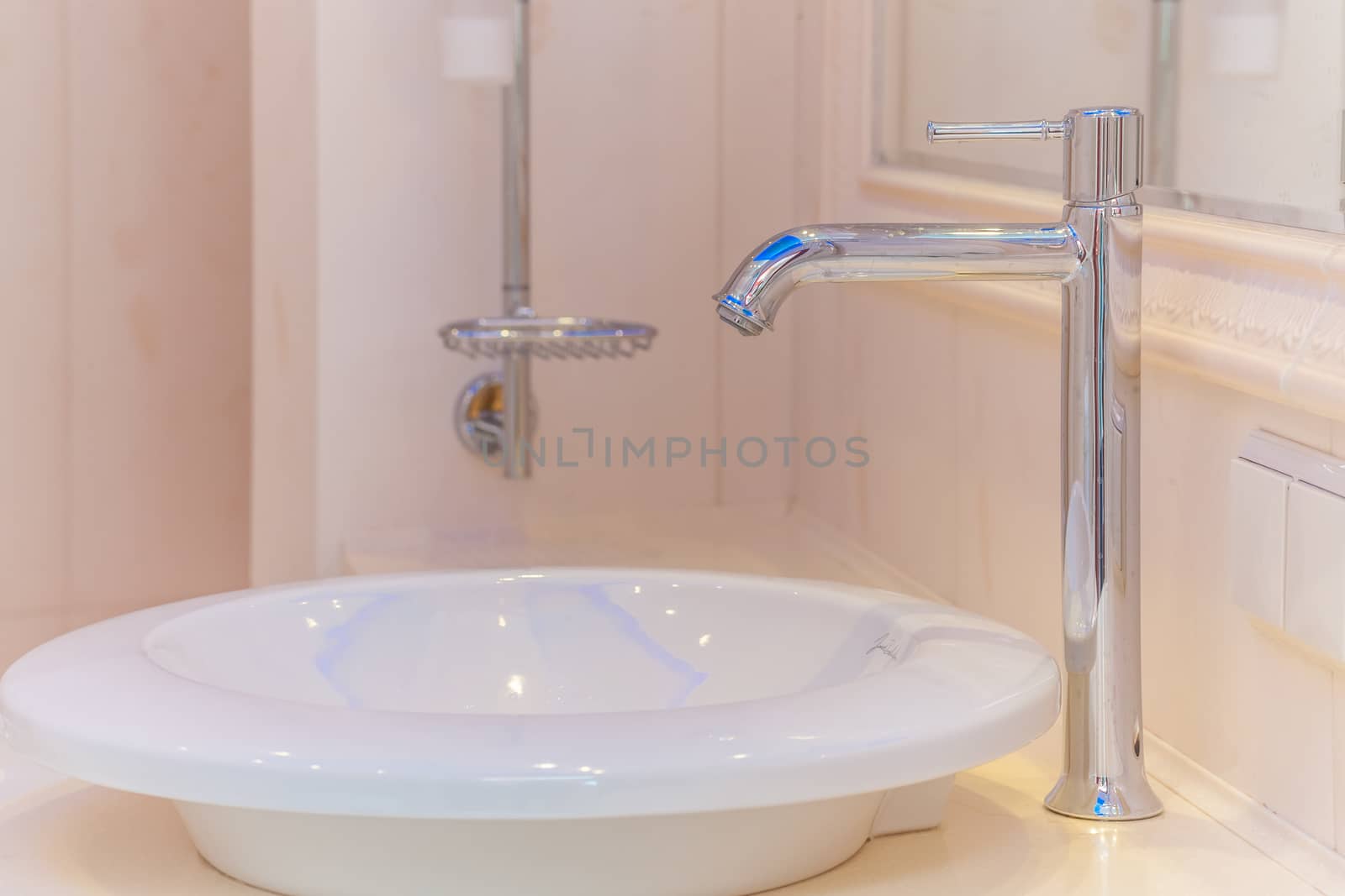 Close up of modern faucet and ceramic sink in bathroom