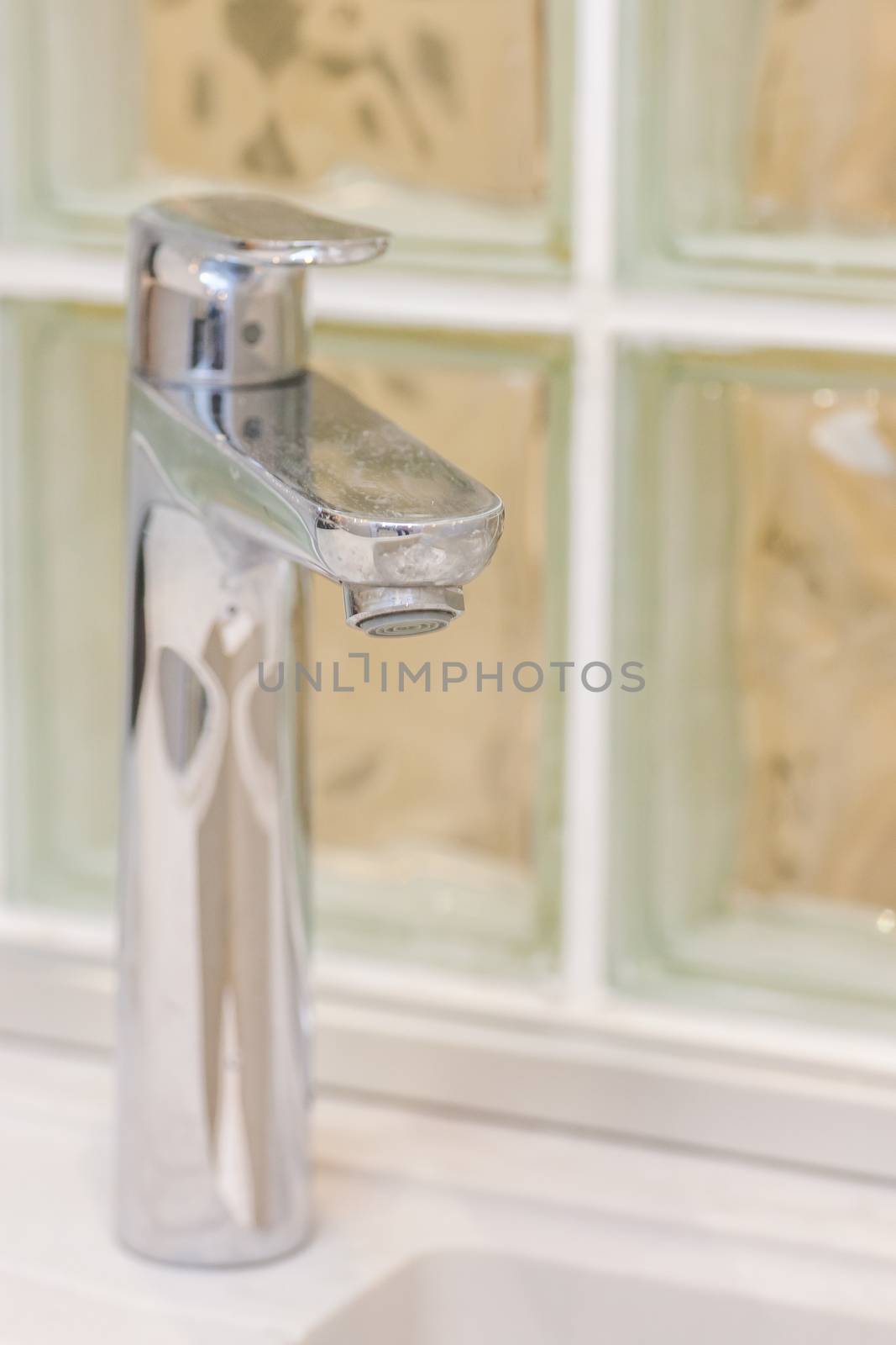 Close up of modern faucet and ceramic sink in bathroom