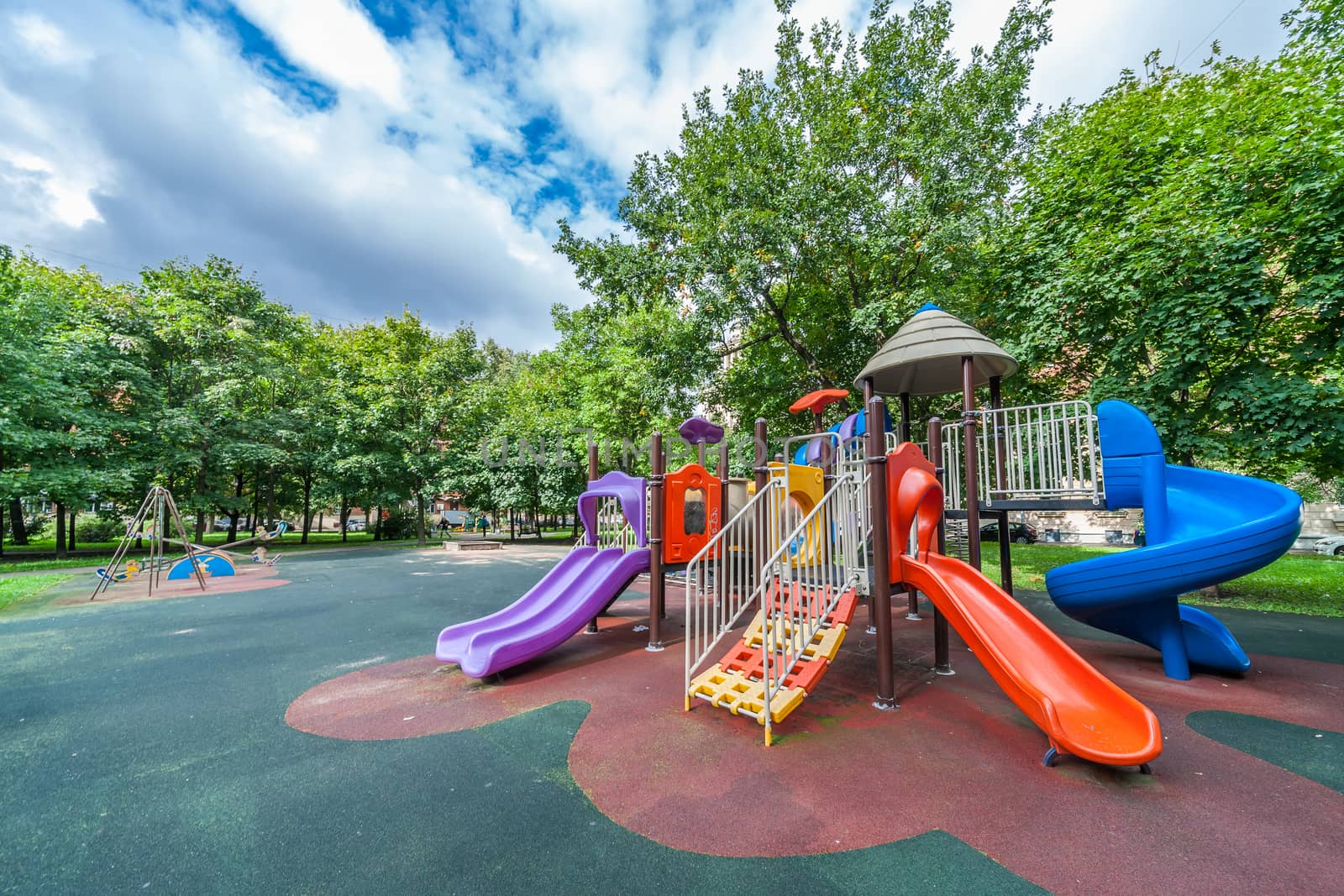 Colorful playground equipment for children in public park in summer