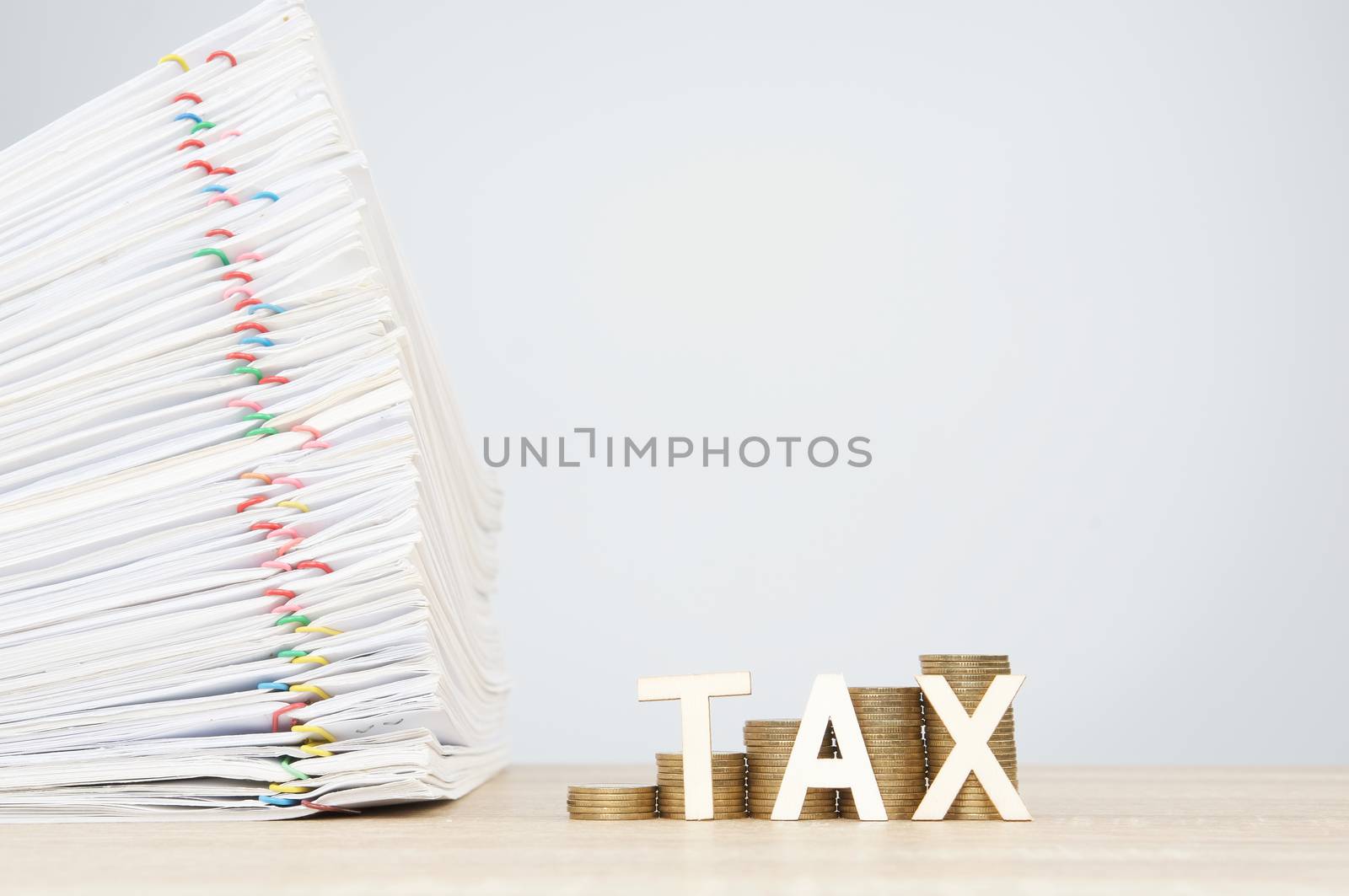 Tax letters and step pile of gold coins with overload document report of sale and papercilp on wooden table with white background and copy space. Business and finance concept rich and successful.