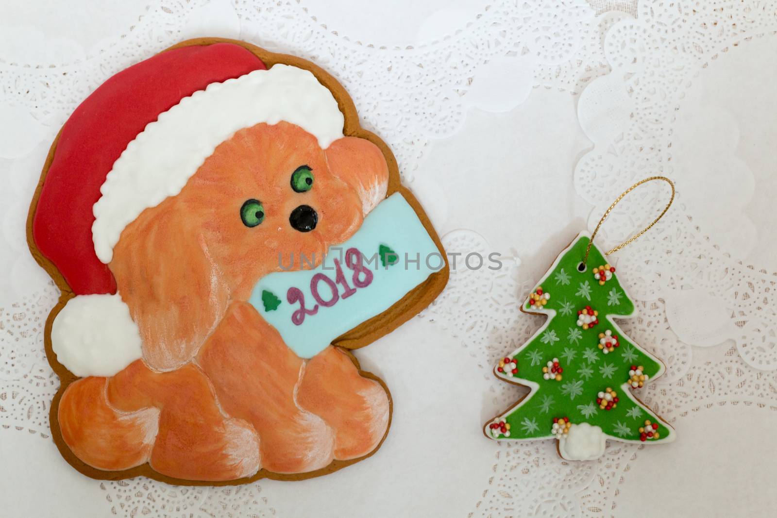 Two gingerbread cookies in the shape of Christmas tree and dog on a white napkin background. Top view, flat lay, copy space. Curly Christmas gingerbread home cooking. Happy new year 2018