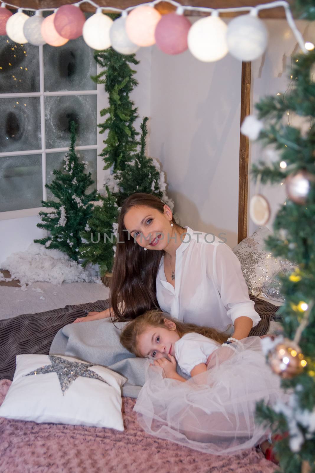 Mother and daughter in winter studio lying cosy