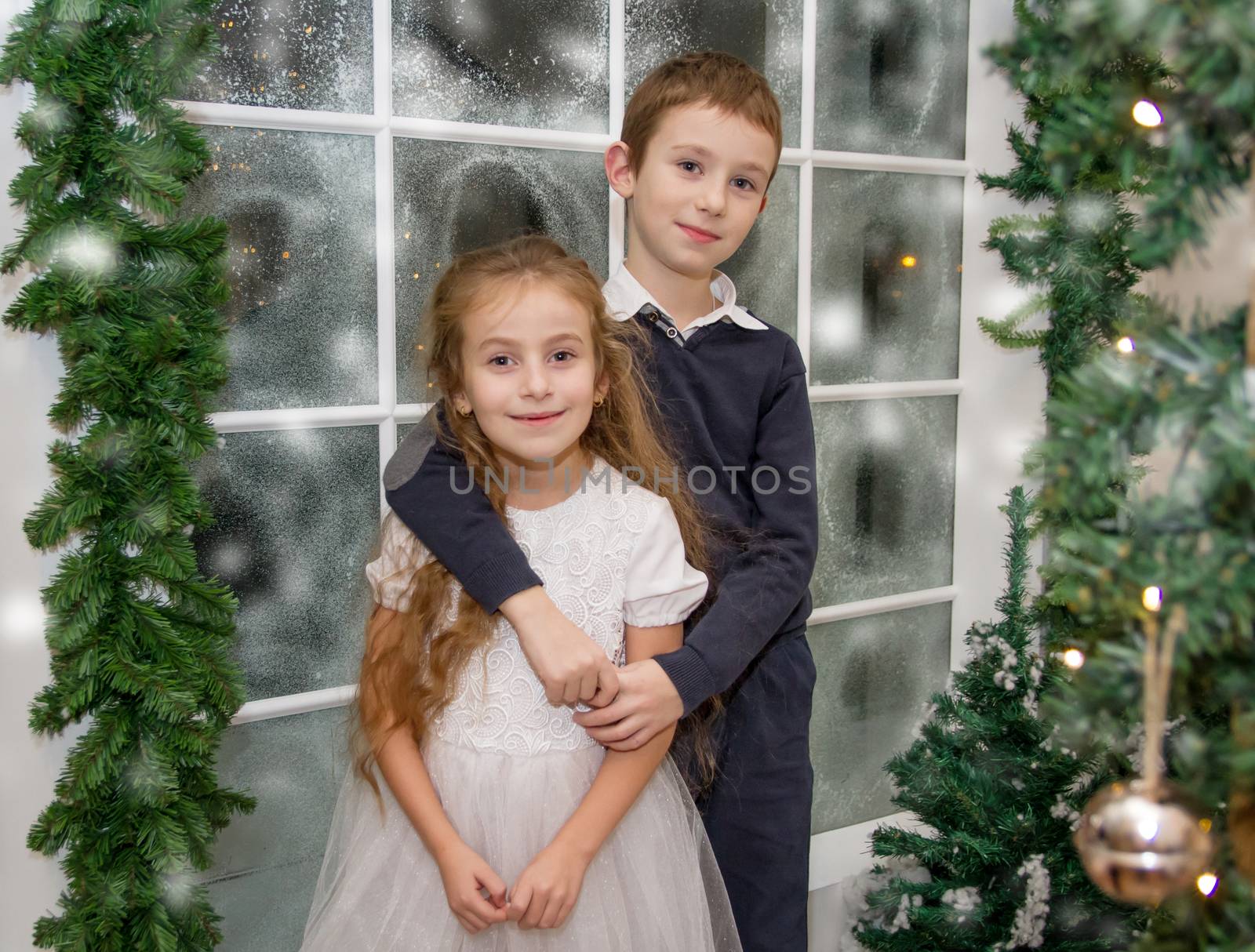 Smiling sister and brother in winter studio hugging