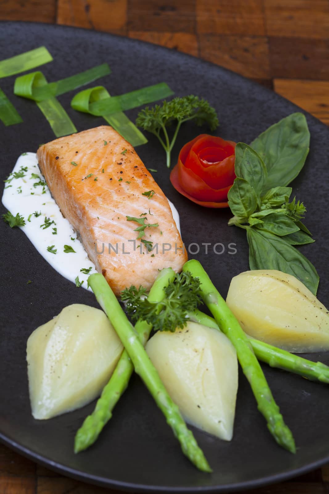 Atlantic salmon with a rocket salad,Decorated with vegetables on a black plate.