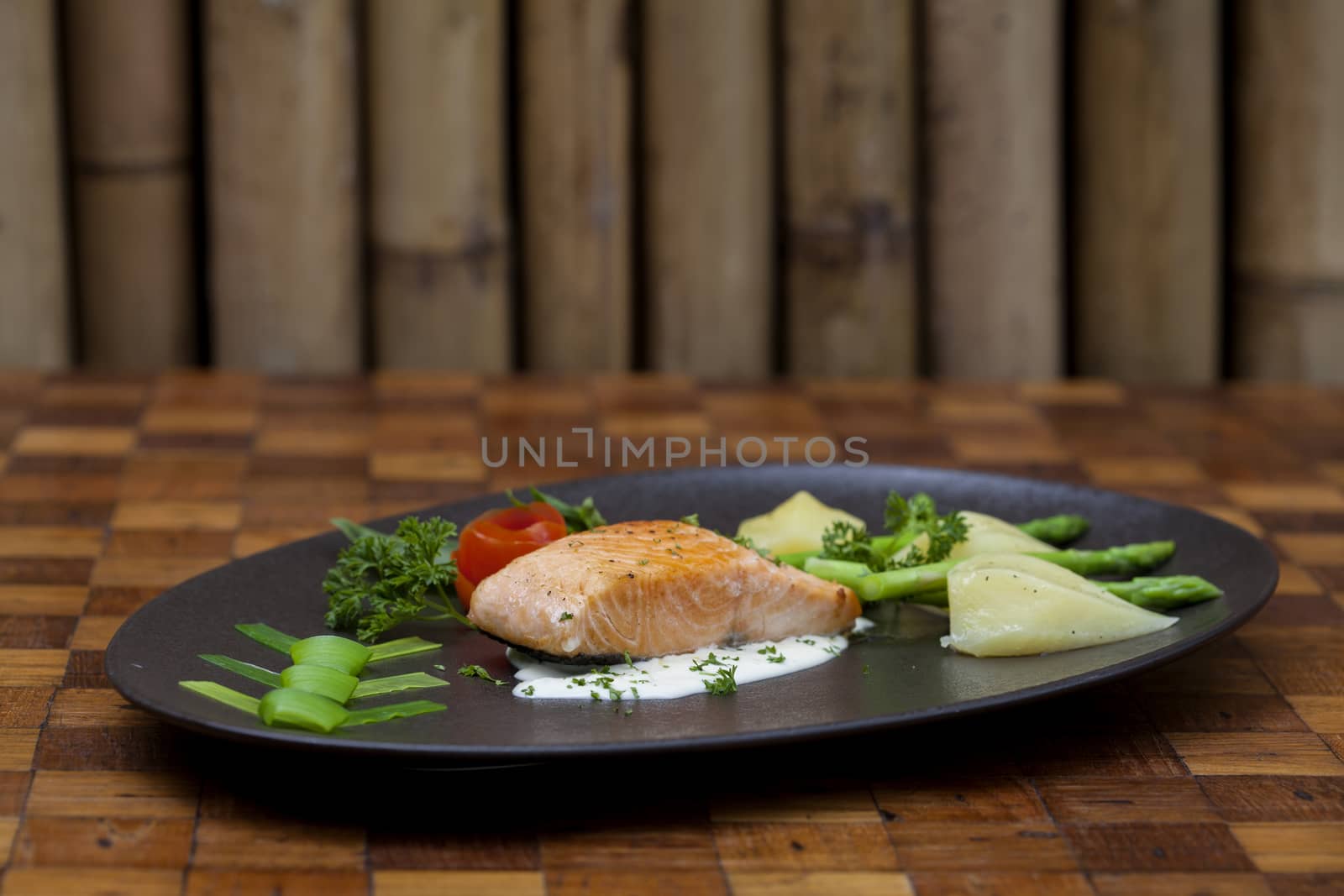 Atlantic salmon with a rocket salad,Decorated with vegetables on a black plate.