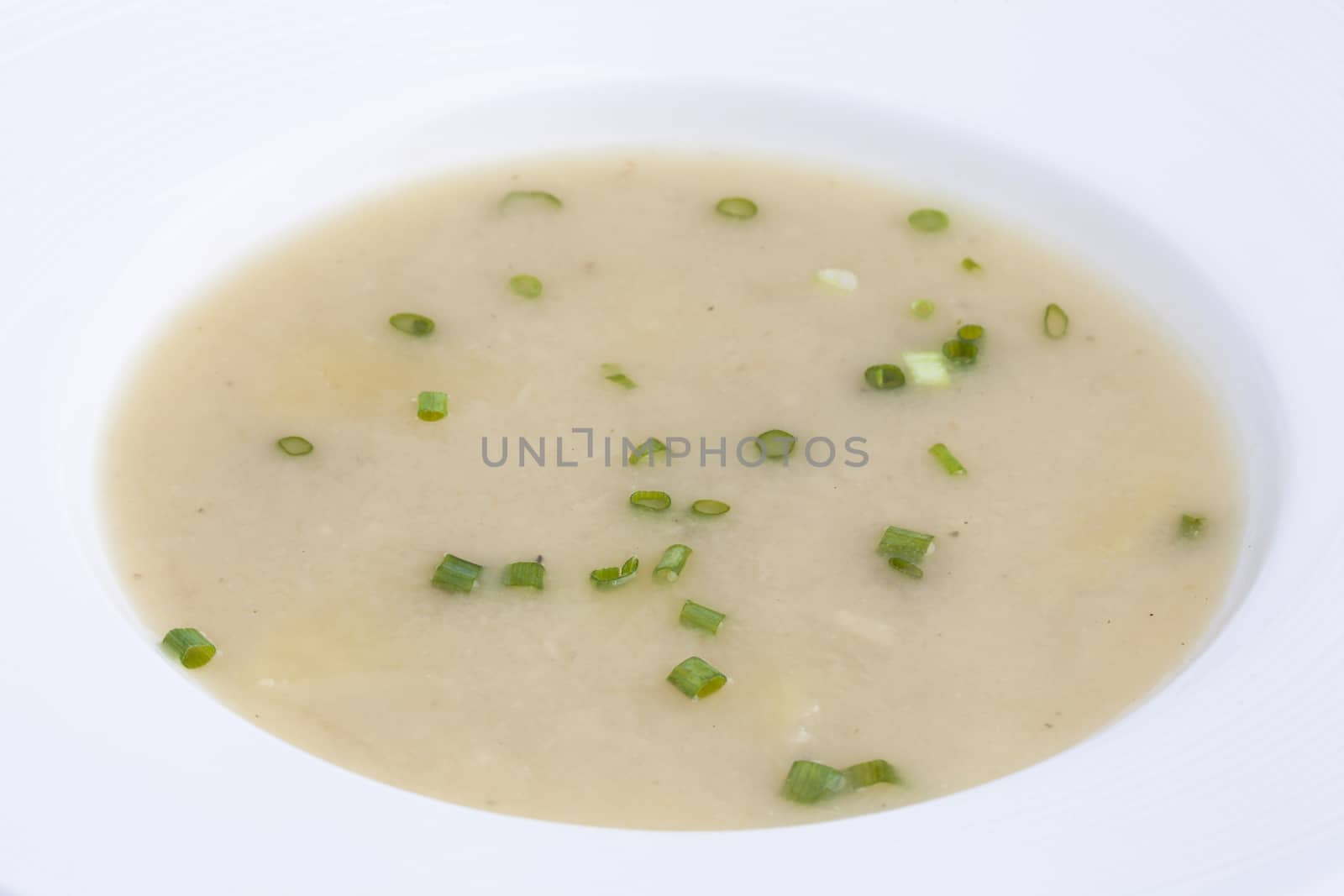 cream soup in a plate top view soup decorated with green onions by jee1999